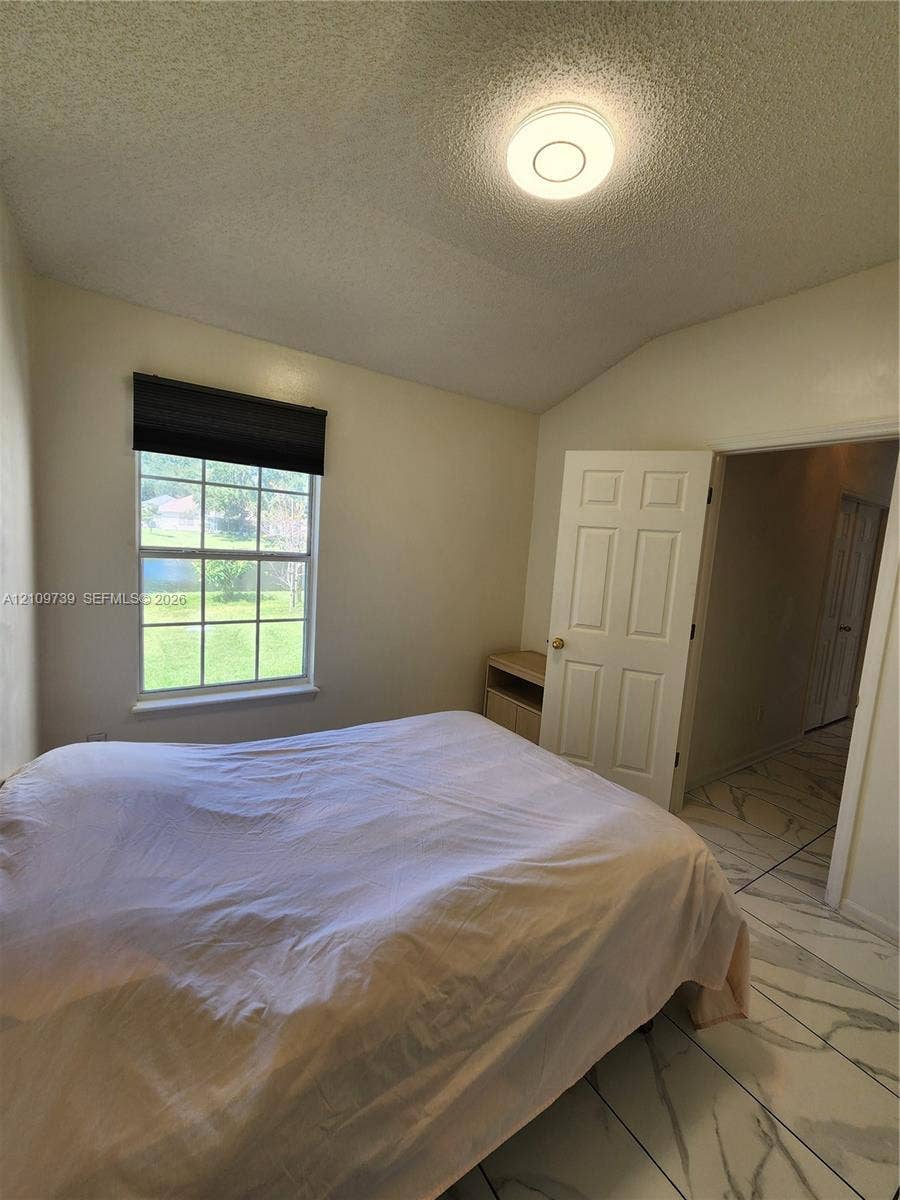 Vaulted ceilings, large-format tile flooring with marble-style veining, and a single-pane window with grid detailing