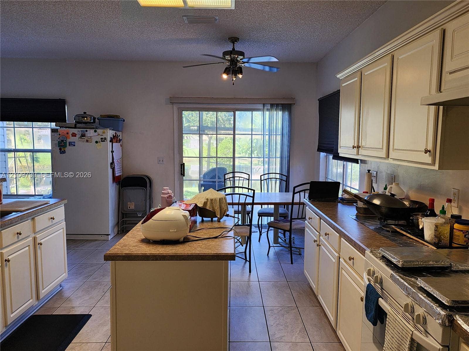 Kitchen featuring neutral cabinetry, a central island with countertop, tile flooring, and sliding glass doors