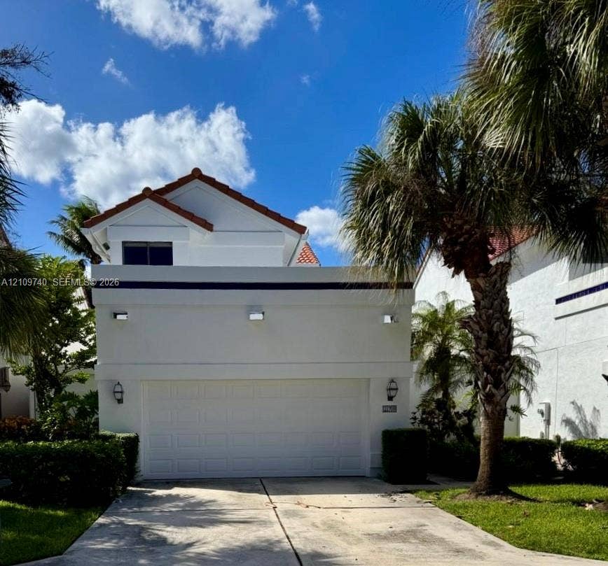 Single-family home in Boca Raton with a tiled roof, attached two-car garage, and mature palm trees