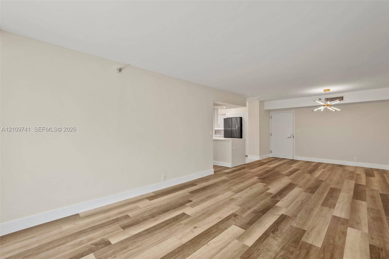 19101 NE 36th Court, #203, Aventura, FL 33180 Open-concept interior featuring wood-finish plank flooring, neutral wall tones, and a modern sputnik-style chandelier