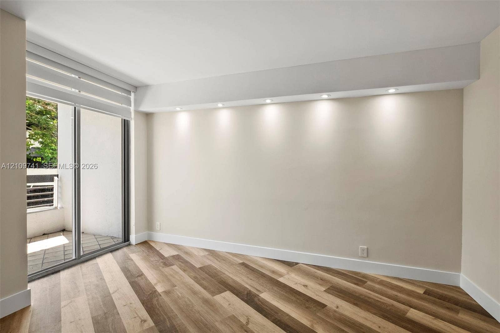 19101 NE 36th Court, #203, Aventura, FL 33180 Wood-finish flooring, recessed soffit lighting, and sliding glass door with access to a private balcony