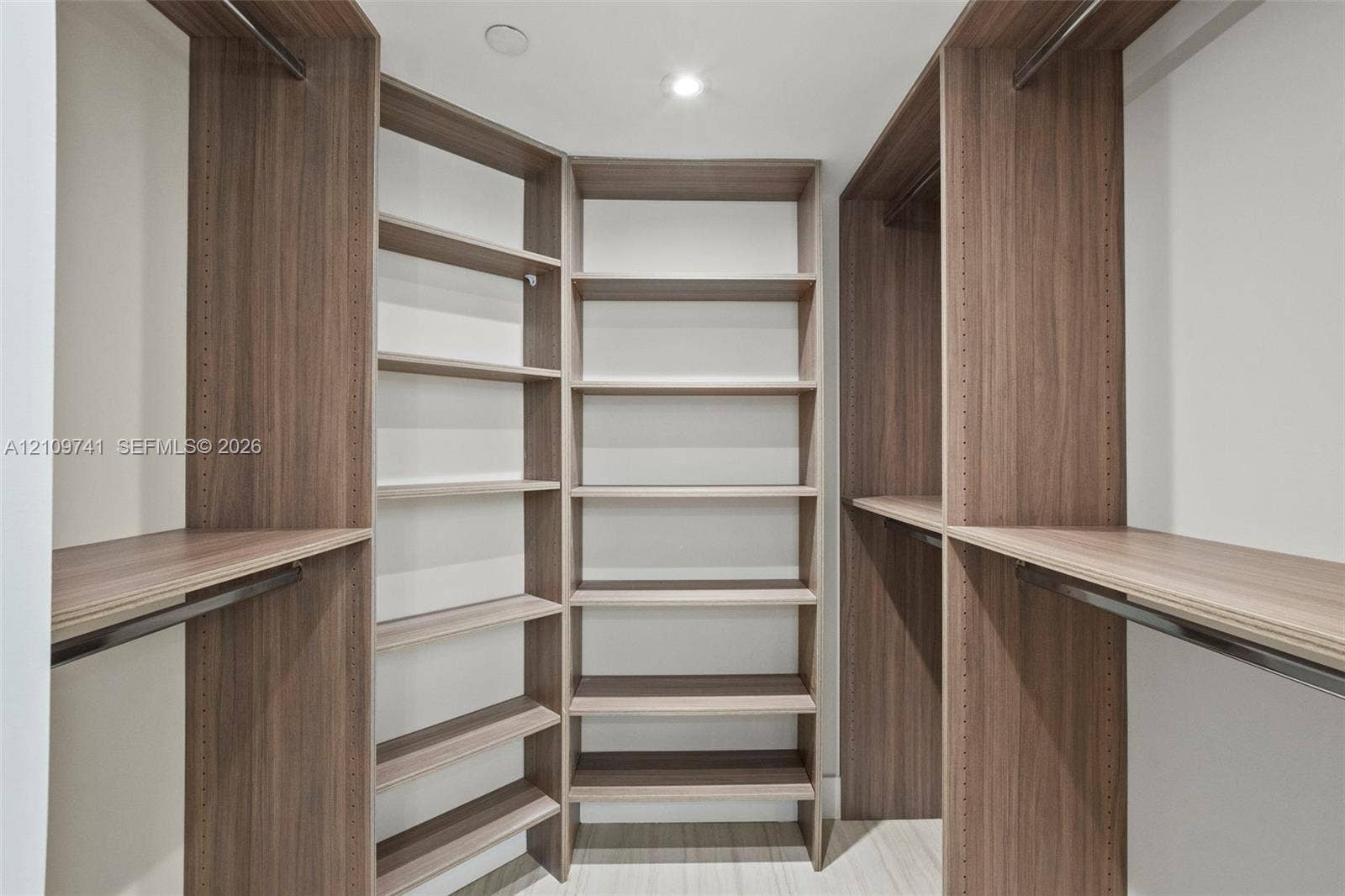 19101 NE 36th Court, #203, Aventura, FL 33180 Custom walk-in closet featuring wood-finish cabinetry, built-in shelving units, integrated hanging rods, and recessed lighting