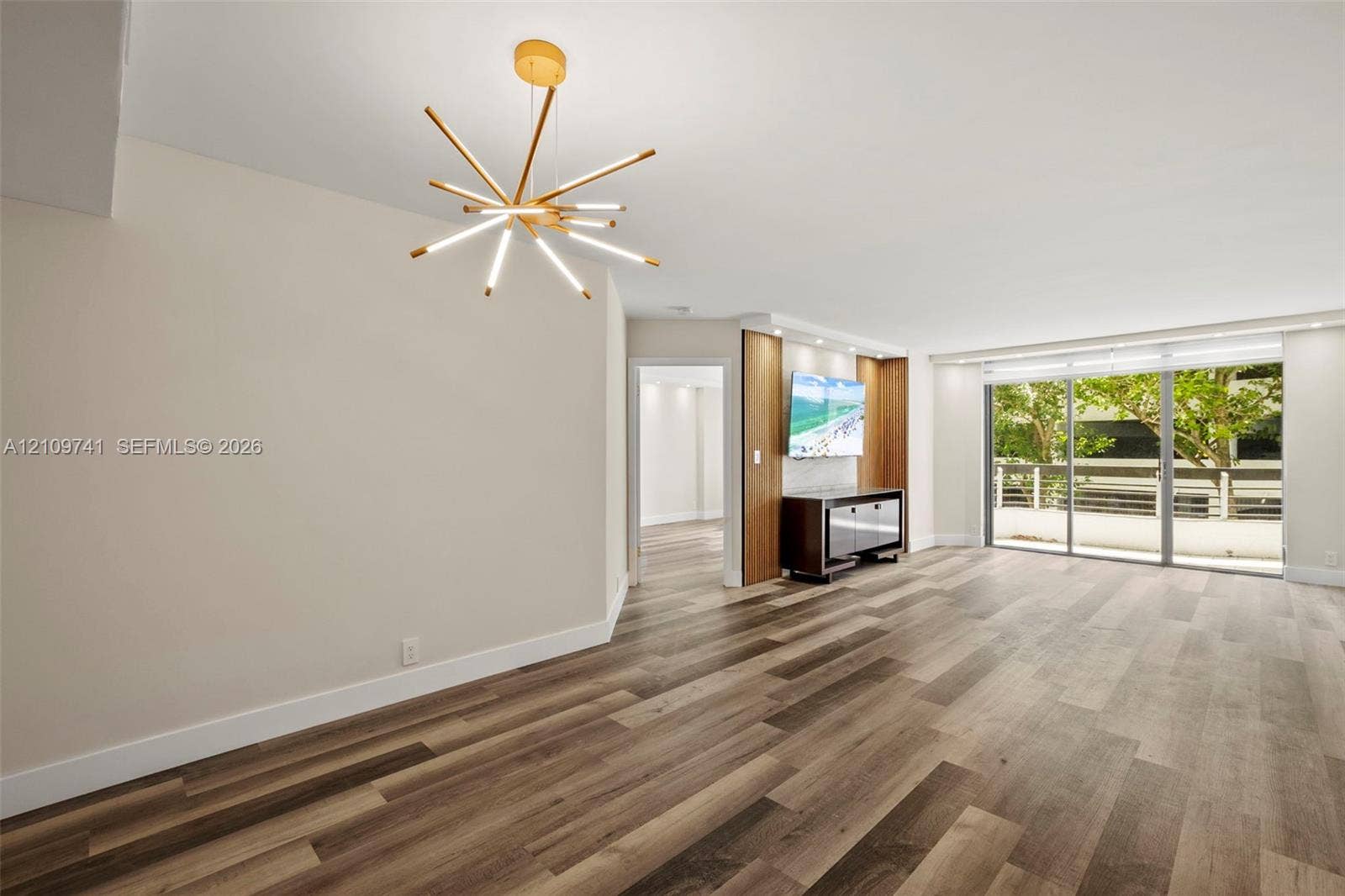 19101 NE 36th Court, #203, Aventura, FL 33180 Wood-finish flooring, multi-arm contemporary pendant light, custom built-in cabinetry with integrated accent lighting, and expansive sliding glass doors