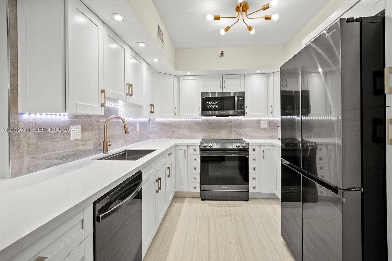 19101 NE 36th Court, #203, Aventura, FL 33180 Kitchen featuring white shaker-style cabinetry, stainless steel appliances, stone-surface countertops, under-cabinet lighting, and wood-finish flooring