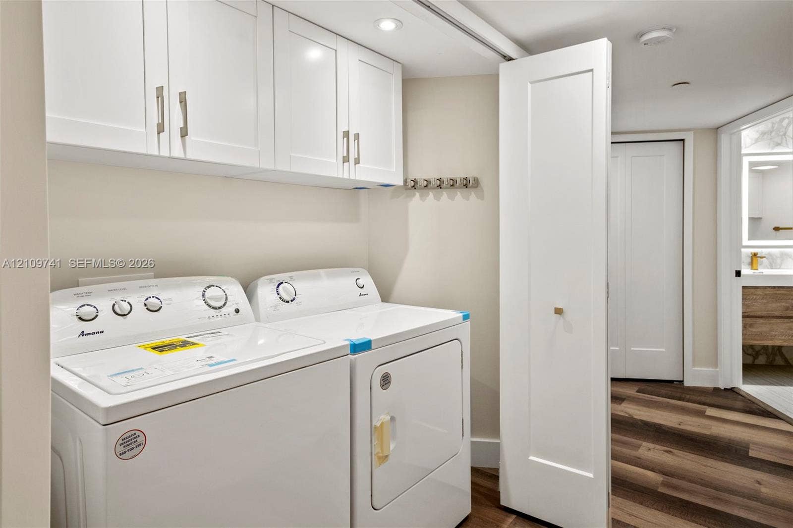 19101 NE 36th Court, #203, Aventura, FL 33180 Laundry area featuring white shaker-style wall cabinetry, recessed lighting, and wood-finish flooring