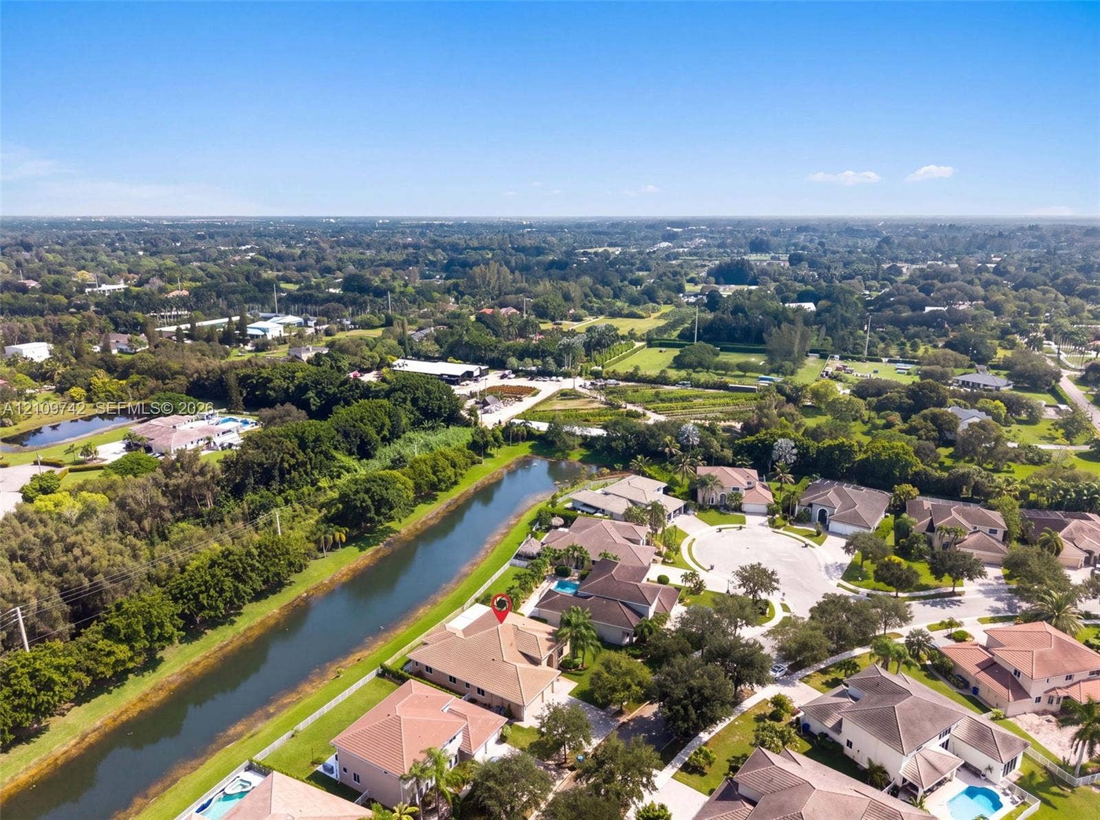 19143 SW 60th Court, Pembroke Pines, FL 33332 Aerial perspective featuring a waterfront property with a tile roof, paved driveway, and mature landscaping