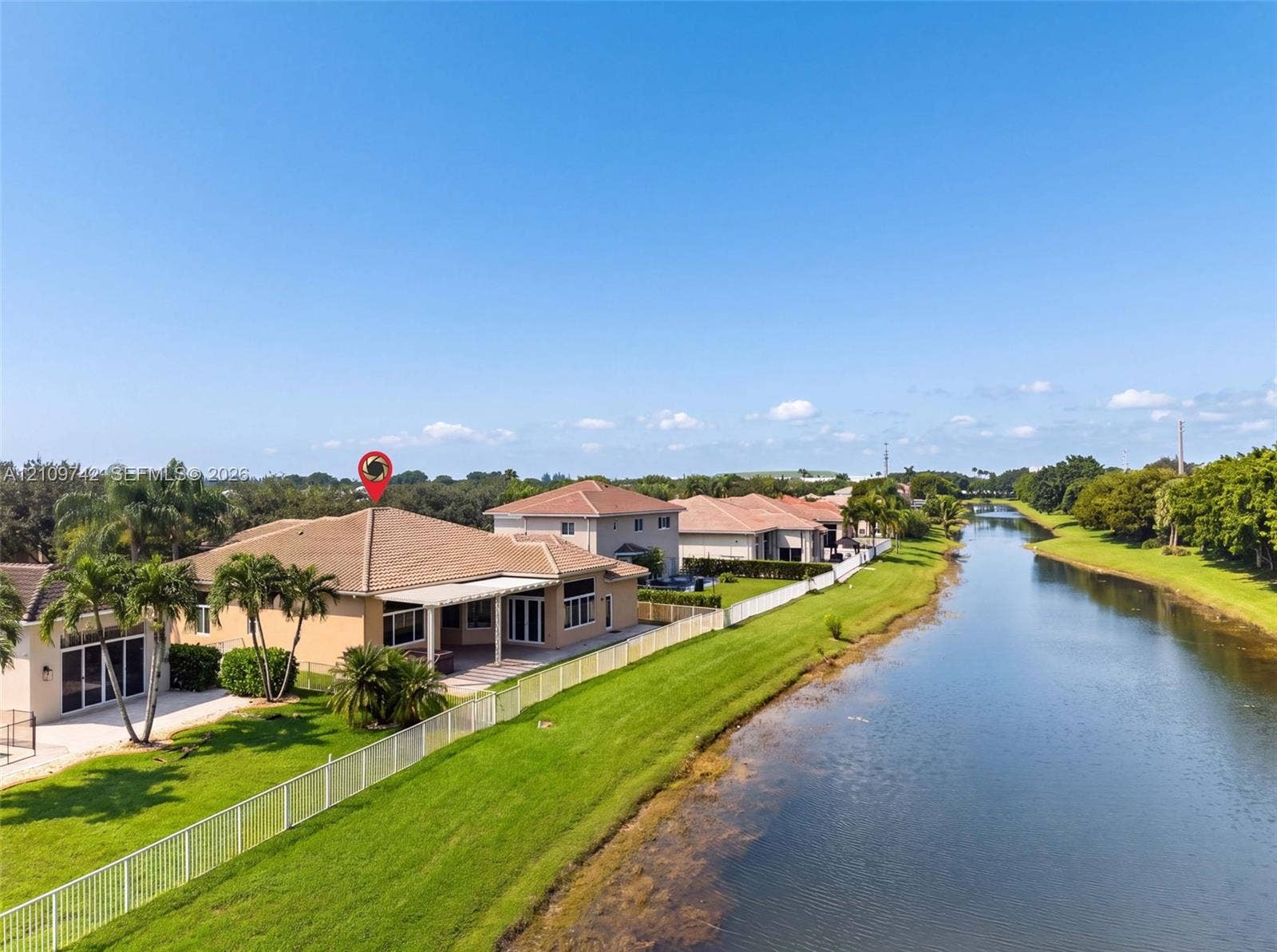 19143 SW 60th Court, Pembroke Pines, FL 33332 Waterfront property featuring a covered patio, tile roof, and perimeter fencing along a canal