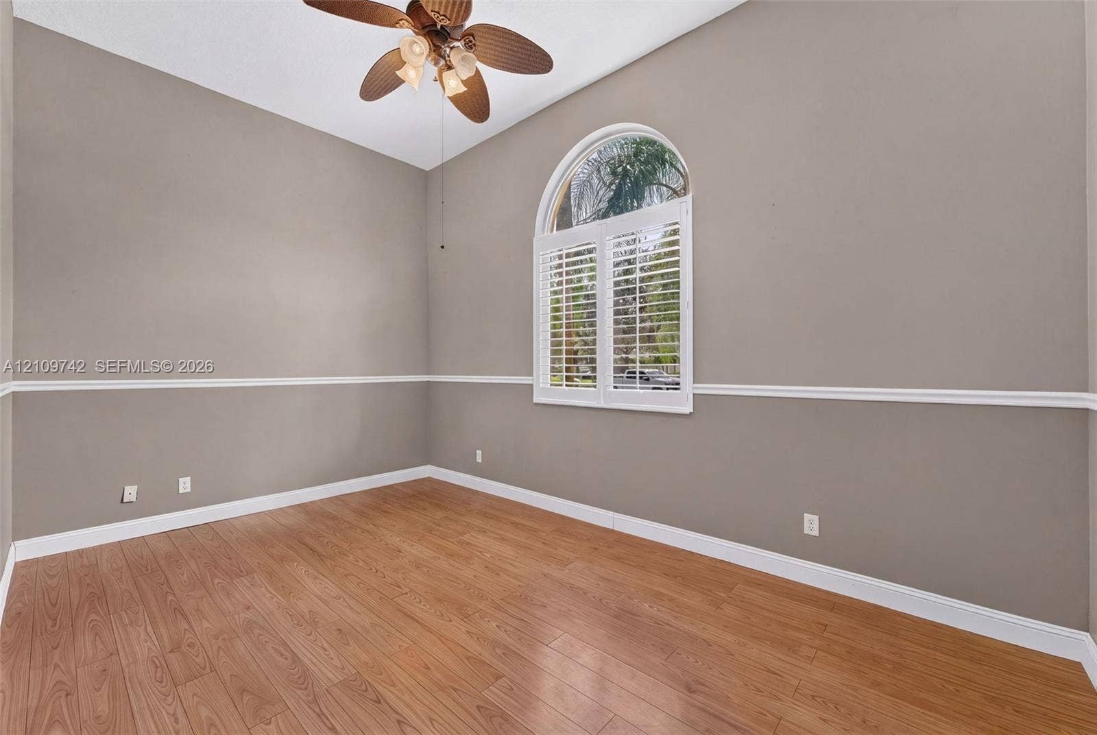 19143 SW 60th Court, Pembroke Pines, FL 33332 Room featuring wood-finish flooring, an arched window with plantation shutters, decorative chair rail molding, and a multi-blade ceiling fan
