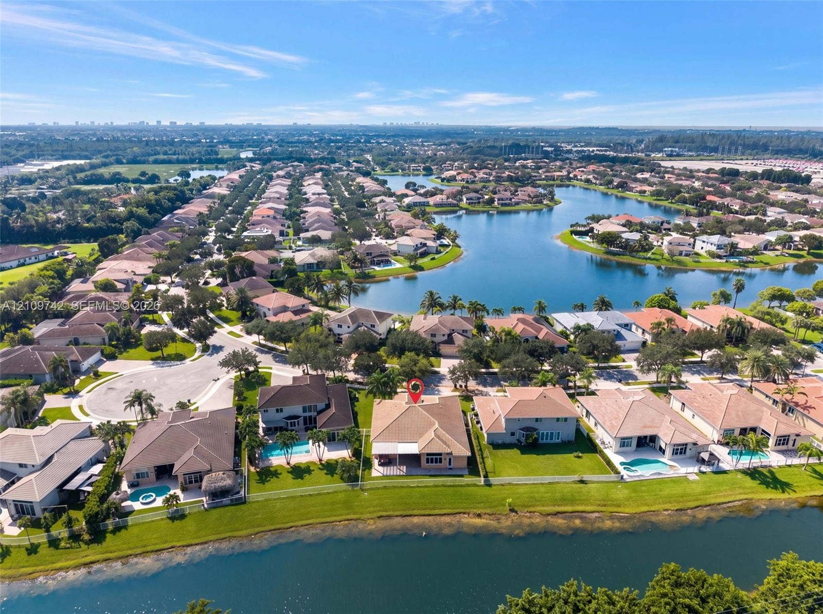 19143 SW 60th Court, Pembroke Pines, FL 33332 Aerial perspective of a residential property featuring a tiled roof, rear covered patio, and direct waterfront placement on a large lake
