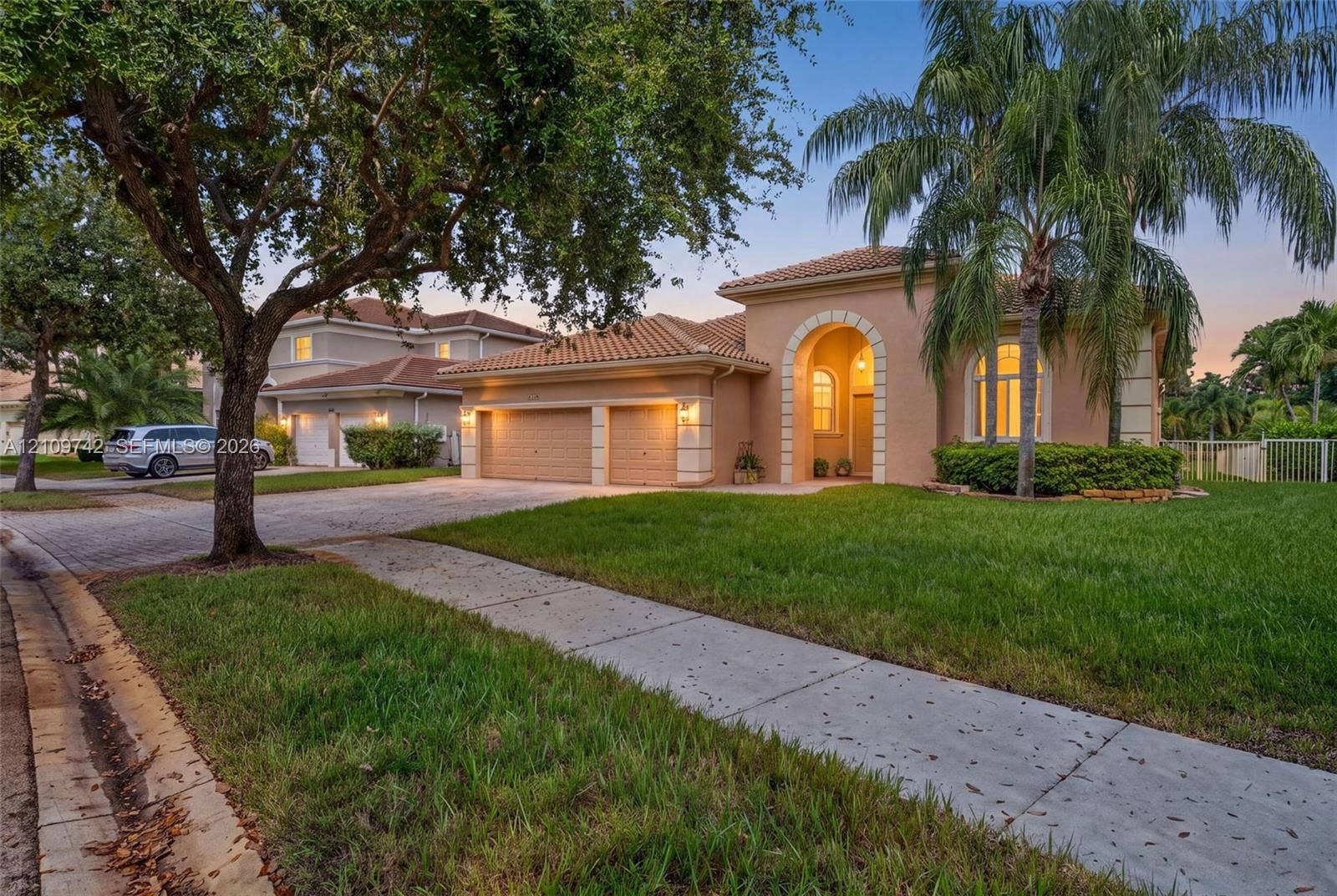 19143 SW 60th Court, Pembroke Pines, FL 33332 Stucco exterior featuring an arched entryway, tile roof, two-car garage, and paved driveway