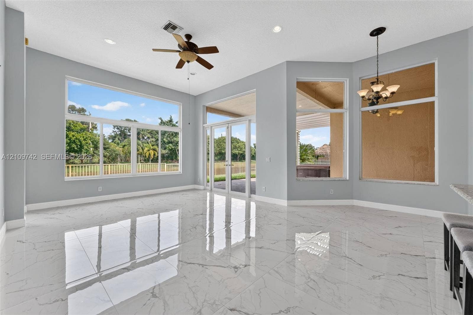19143 SW 60th Court, Pembroke Pines, FL 33332 Polished stone-finish flooring, floor-to-ceiling windows, dual glass entry doors, recessed lighting, and a multi-arm chandelier