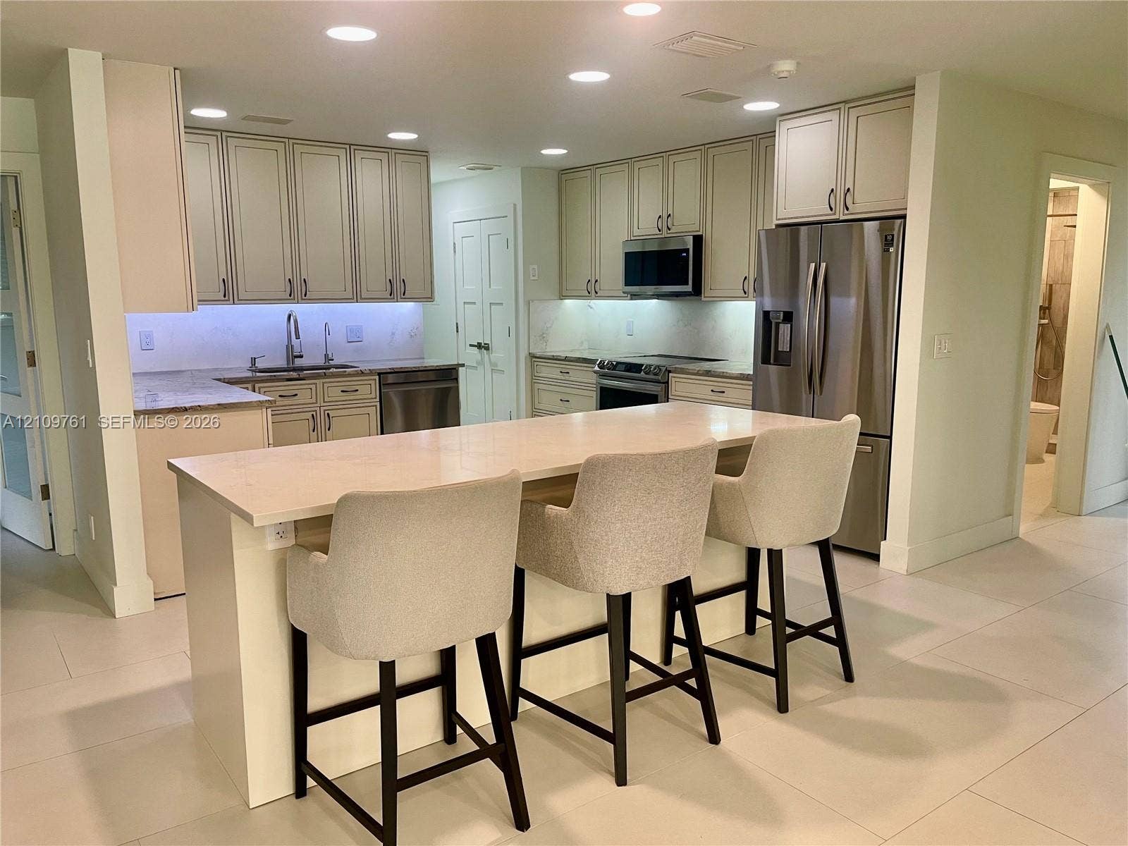Kitchen featuring an expansive center island with quartz countertops, custom cabinetry, stainless steel appliances, and recessed lighting