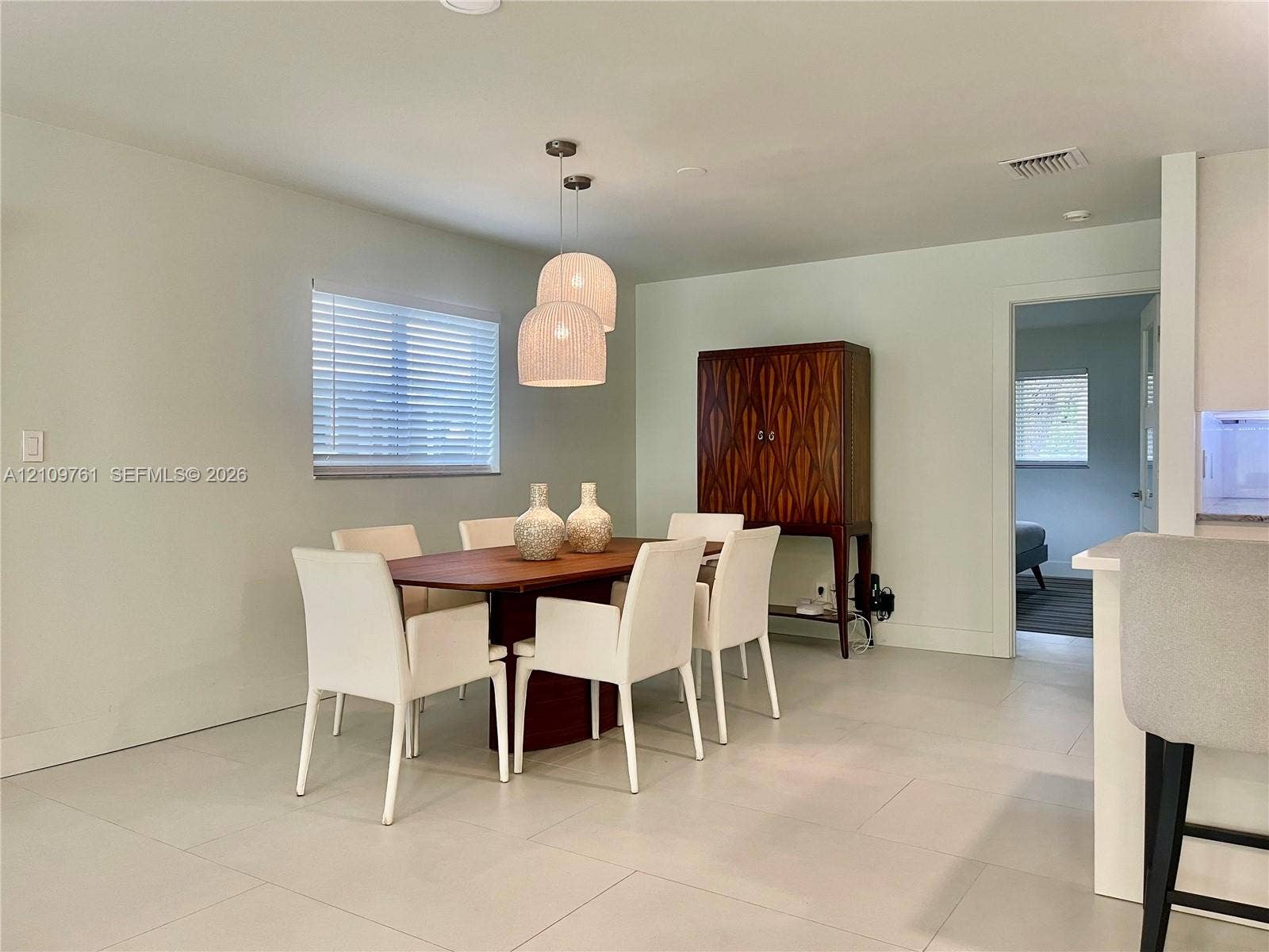 Neutral interior featuring large-format tile flooring, recessed lighting, double pendant lighting fixture, and horizontal blind window treatment