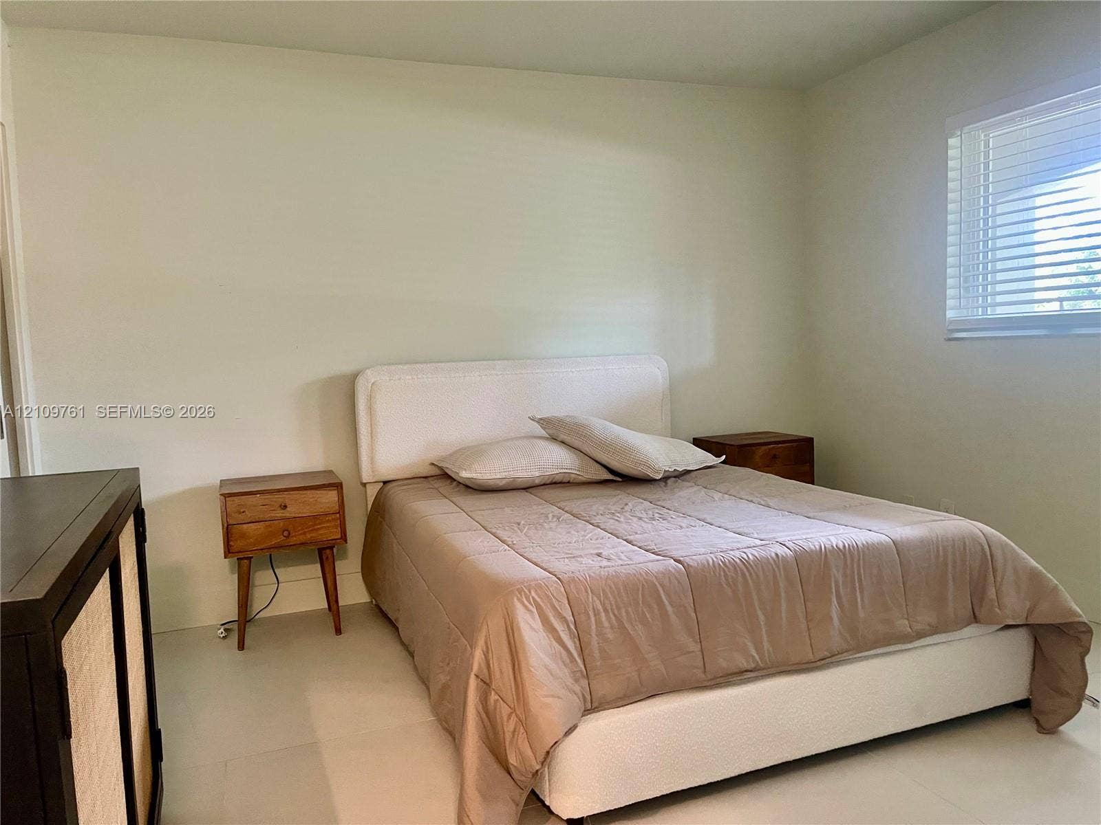 Neutral-toned interior featuring light-colored flooring and a window with horizontal blinds