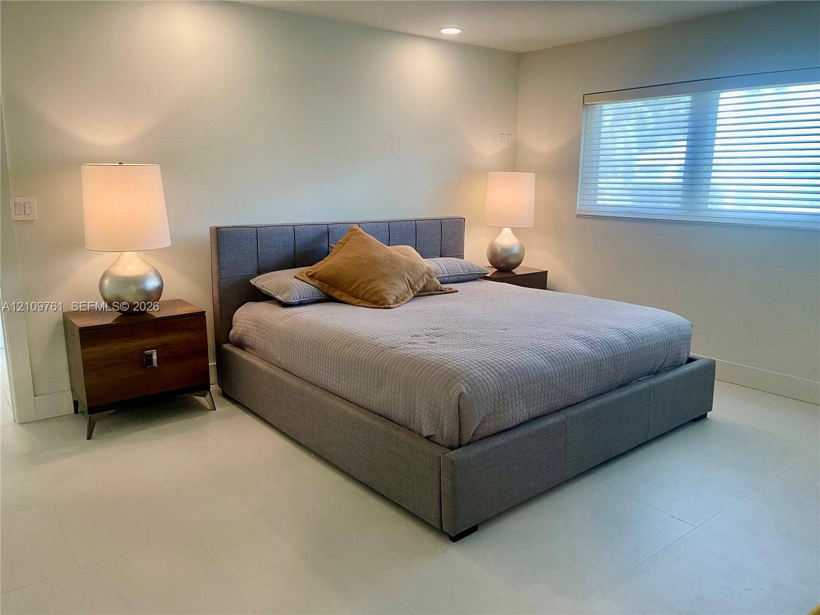 Neutral-toned interior space featuring light-colored flooring, recessed lighting, and a window with horizontal blinds