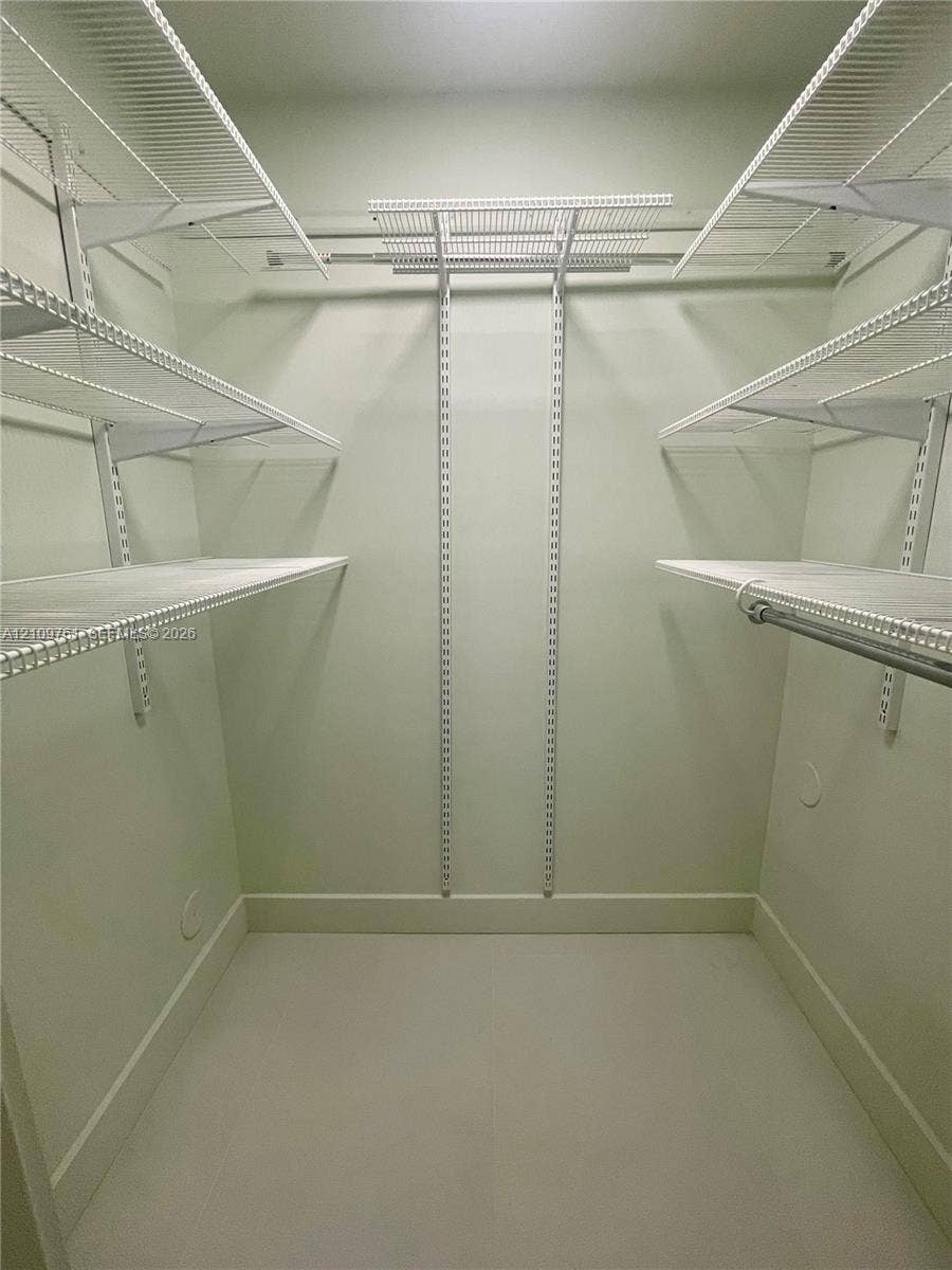 Walk-in closet featuring tiered white wire shelving, adjustable wall-mounted support tracks, and integrated hanging rods