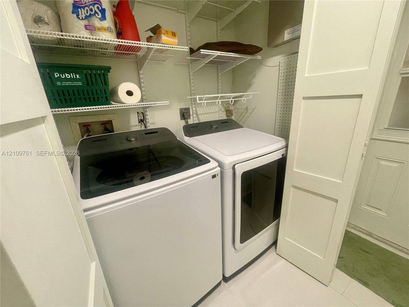 Laundry area featuring white cabinetry doors, multi-tier wire shelving, and a wall-mounted pegboard