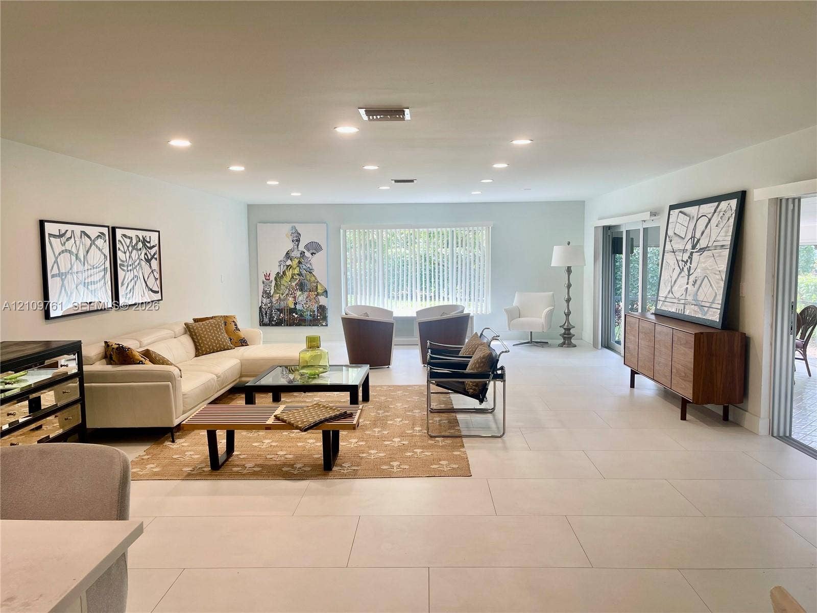 Spacious living area featuring large-format tile flooring, recessed ceiling lighting, and sliding glass doors