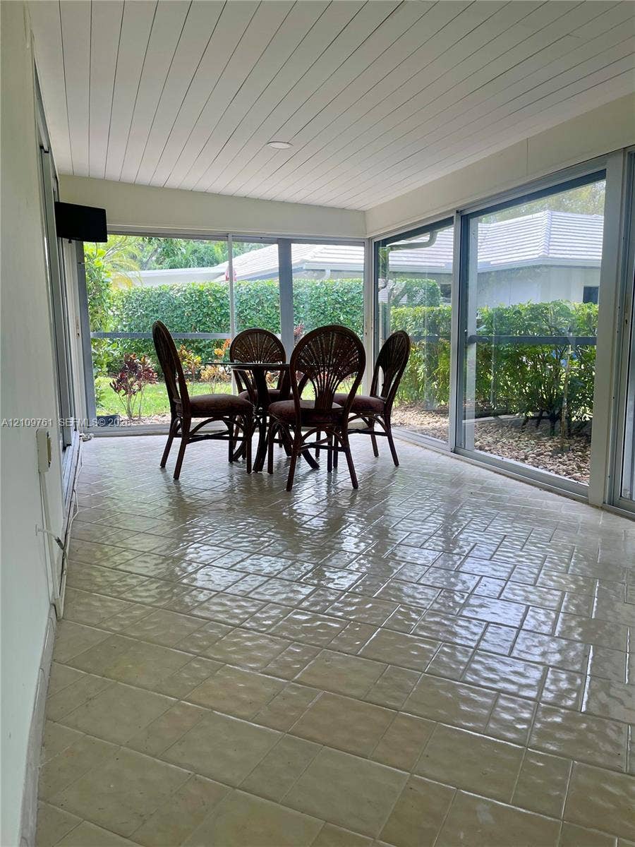 Enclosed patio featuring floor-to-ceiling glass paneling, tile flooring, and a beadboard ceiling