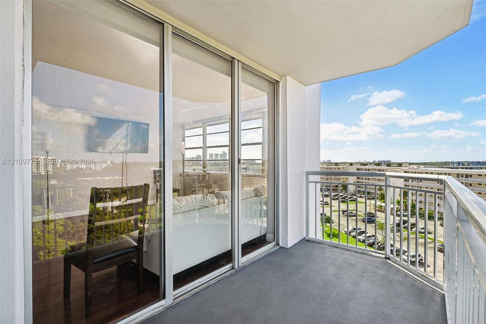 Covered private balcony featuring aluminum railings, floor-to-ceiling sliding glass doors, and solid surface flooring