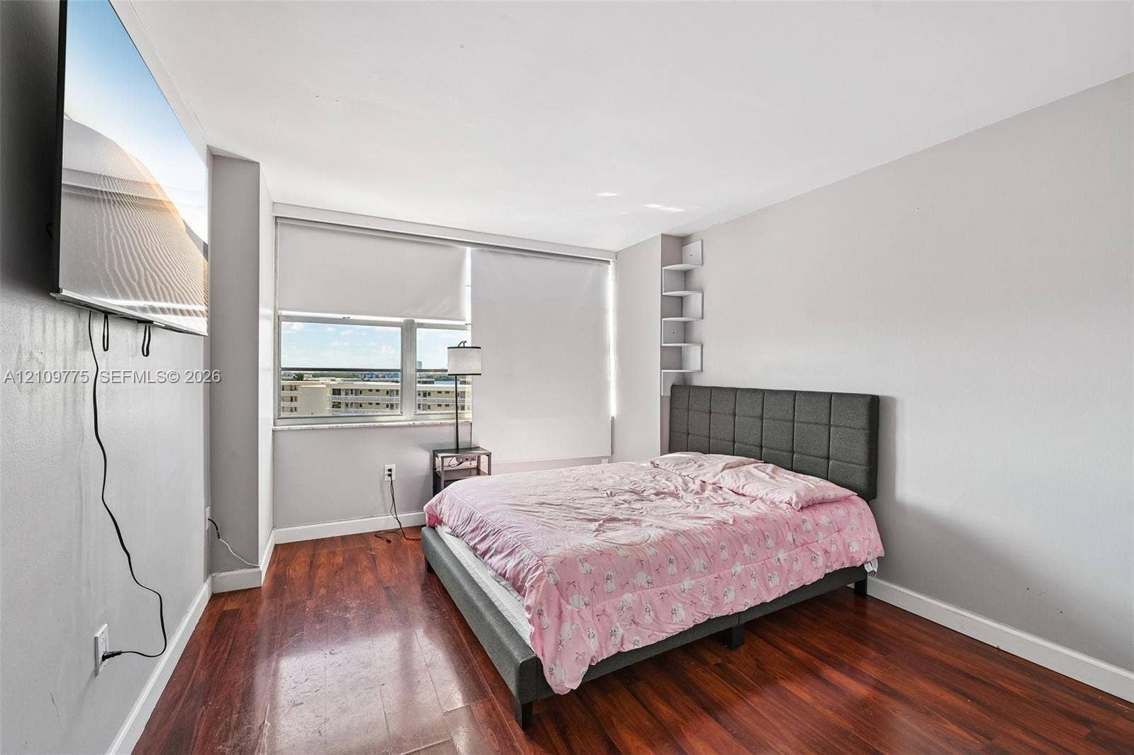 Wood-finish flooring, large windows with roller shades, and integrated floating shelving