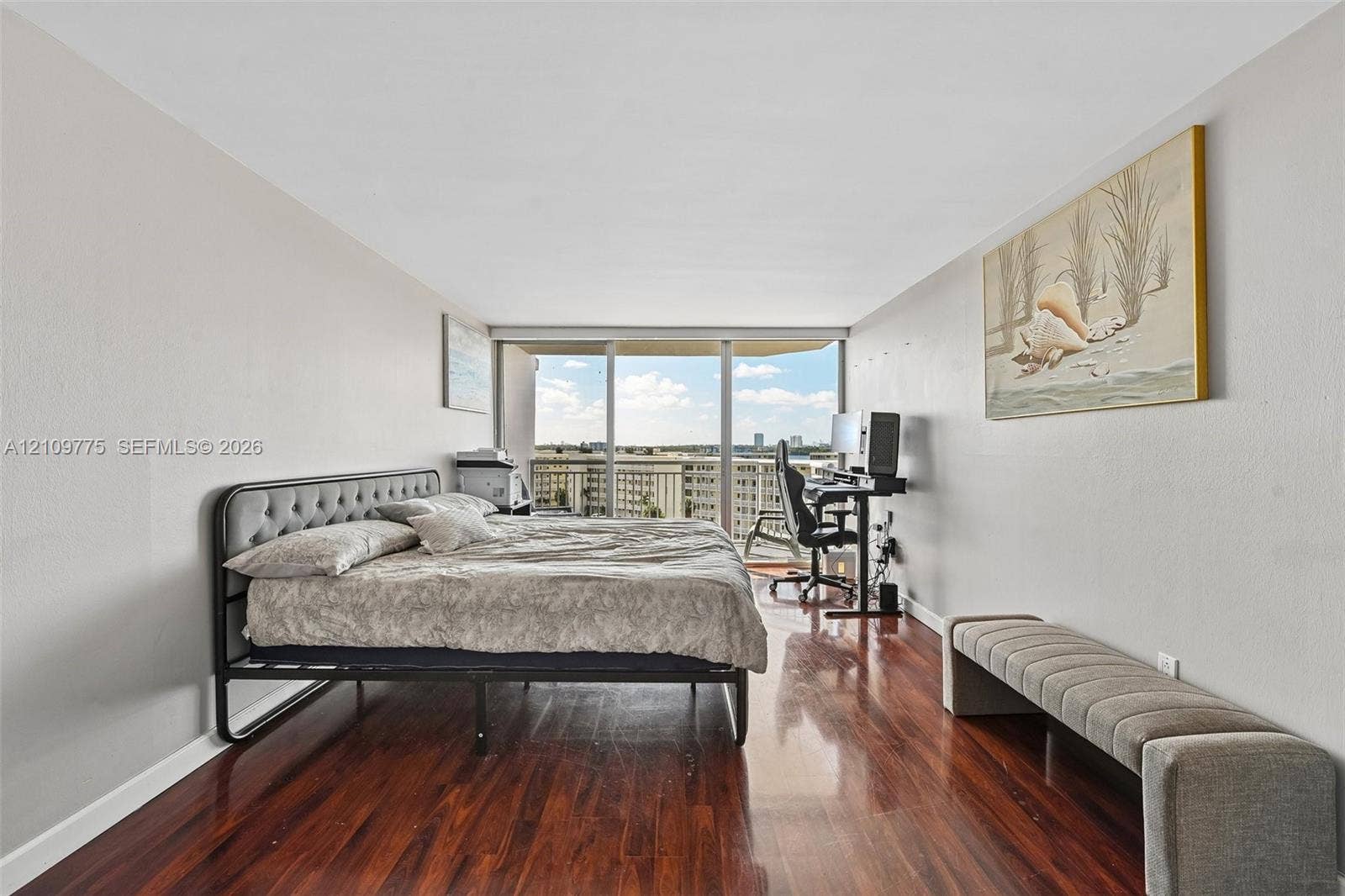 Wood-finish flooring, neutral wall tones, and floor-to-ceiling glass sliding doors opening to an exterior balcony