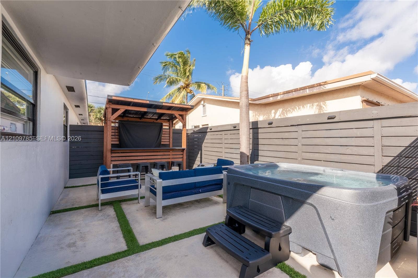 1469 NW 10th Street, #1471, Dania, Dania Beach, FL 33004 Outdoor living area featuring a concrete patio with turf-grid detailing, a built-in bar, a hot tub, privacy fencing