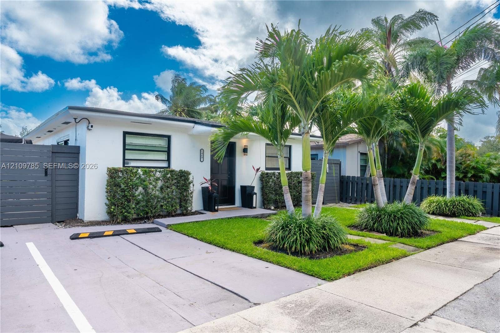 1469 NW 10th Street, #1471, Dania, Dania Beach, FL 33004 Exterior facade featuring privacy fencing, parking, and curated landscaping with mature palm trees