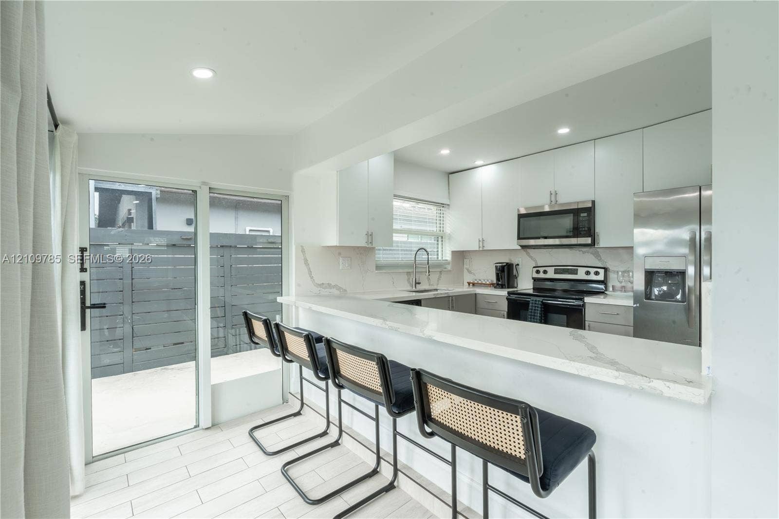 1469 NW 10th Street, #1471, Dania, Dania Beach, FL 33004 Kitchen featuring flat-panel cabinetry, stone-finish countertops with waterfall edge, stainless steel appliances, and large-format tile flooring