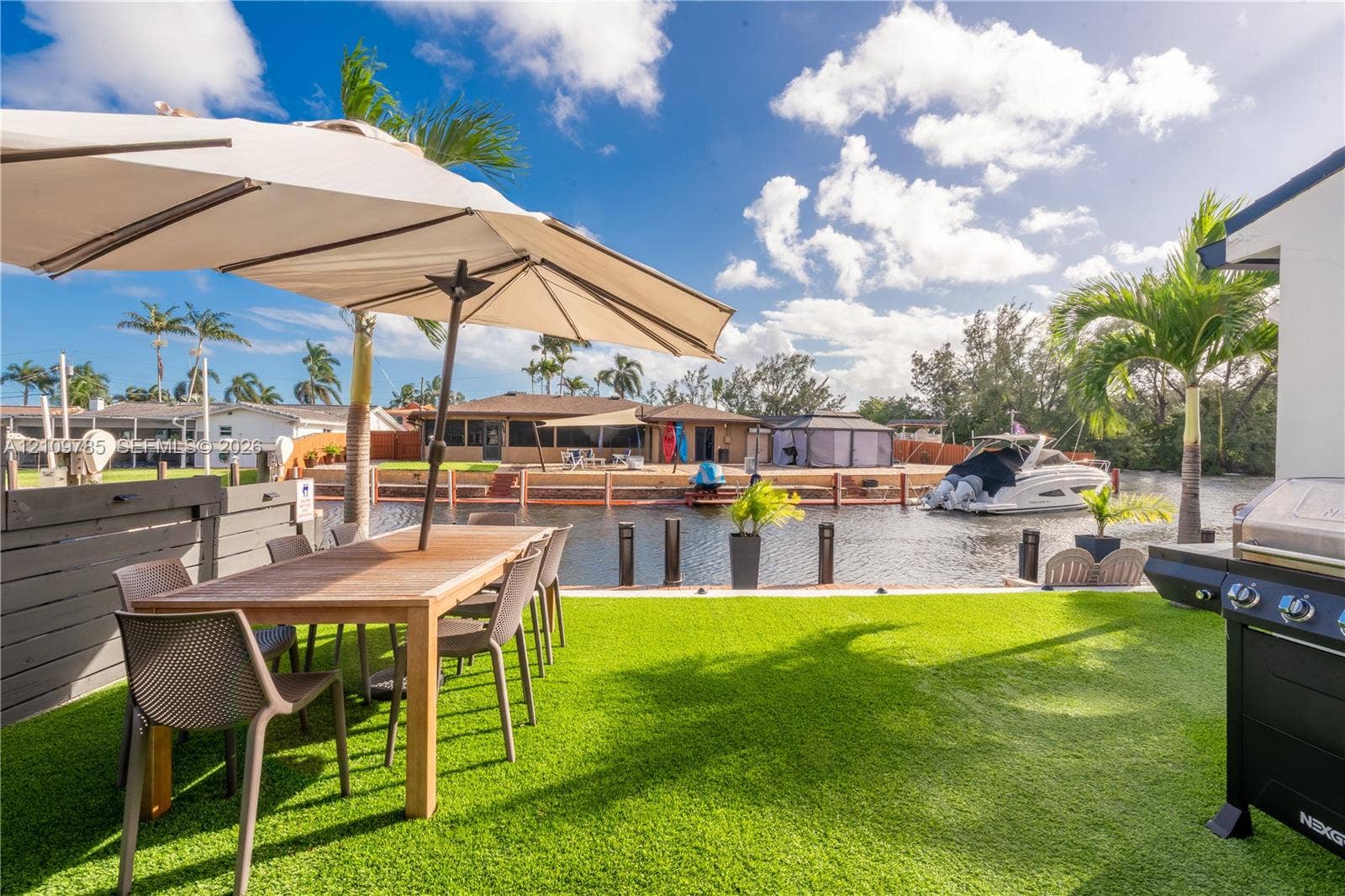1469 NW 10th Street, #1471, Dania, Dania Beach, FL 33004 Waterfront patio featuring synthetic turf, wood-tone fencing, and direct canal access with bulkhead docking