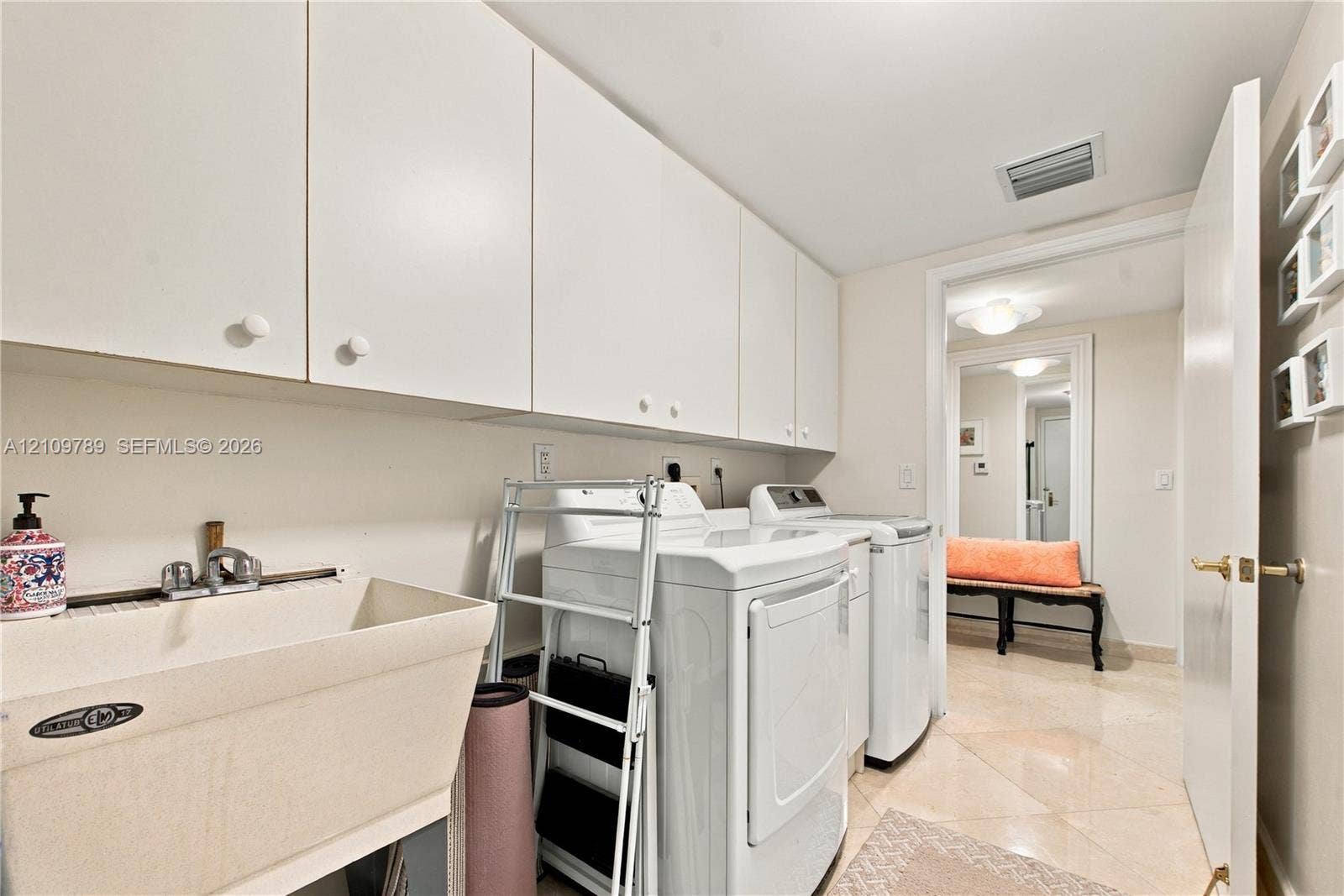 9595 Collins Avenue, #N6-B, Surfside, Surfside, FL 33154 Laundry area featuring white flat-panel upper cabinetry, a deep basin utility sink with a chrome faucet, and tile flooring