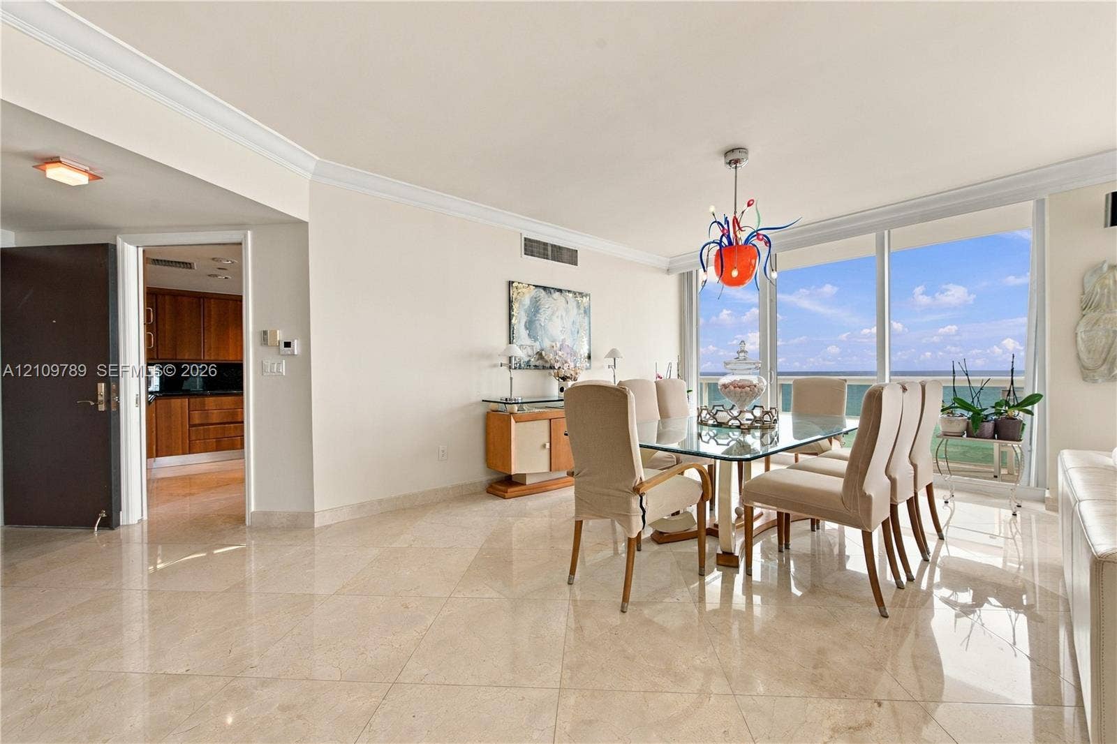 9595 Collins Avenue, #N6-B, Surfside, Surfside, FL 33154 Open-concept dining area featuring polished stone flooring, crown molding, floor-to-ceiling windows, and a decorative chandelier