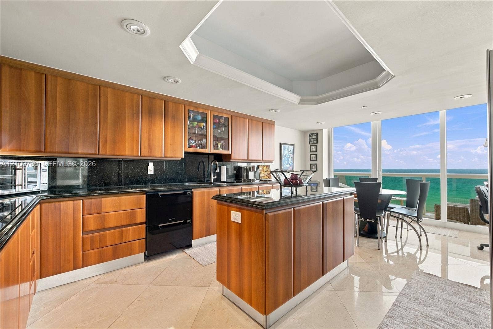 9595 Collins Avenue, #N6-B, Surfside, Surfside, FL 33154 Kitchen featuring custom wood cabinetry, dark stone countertops, central island, recessed tray ceiling, and floor-to-ceiling windows with ocean scenery