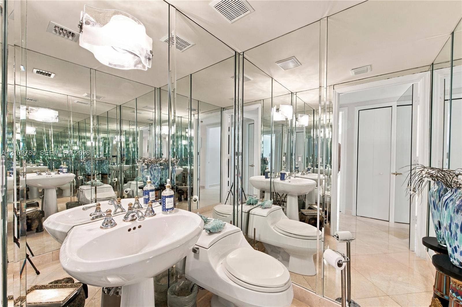9595 Collins Avenue, #N6-B, Surfside, Surfside, FL 33154 Full-wall vanity mirror, dual porcelain pedestal sinks, polished stone flooring, and contemporary pendant lighting