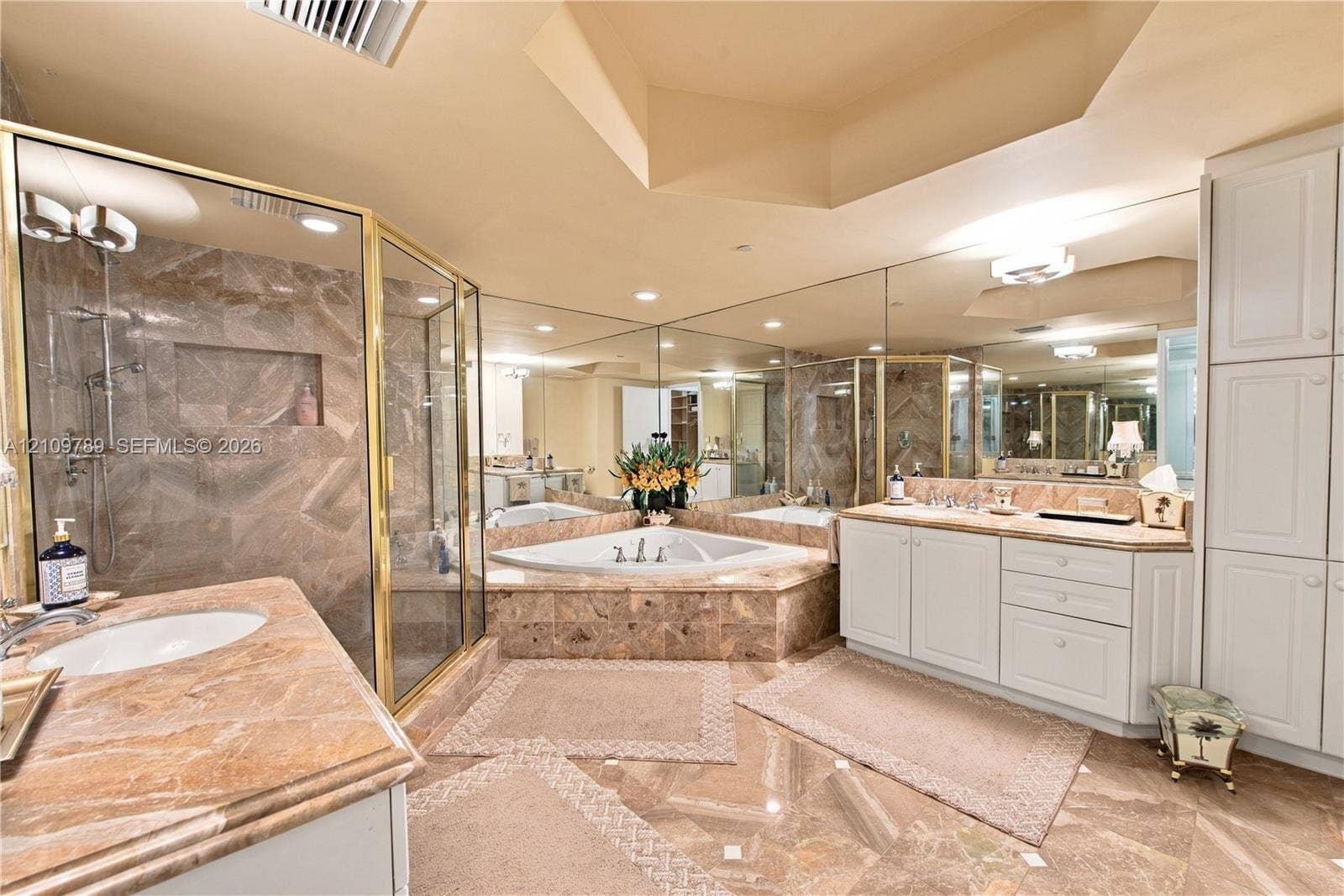9595 Collins Avenue, #N6-B, Surfside, Surfside, FL 33154 Bathroom featuring stone-surface vanity countertops, an oversized corner soaking tub with a stone surround, a glass-enclosed shower, expansive wall-to-wall mirror, and floor-to-ceiling built-in cabinetry