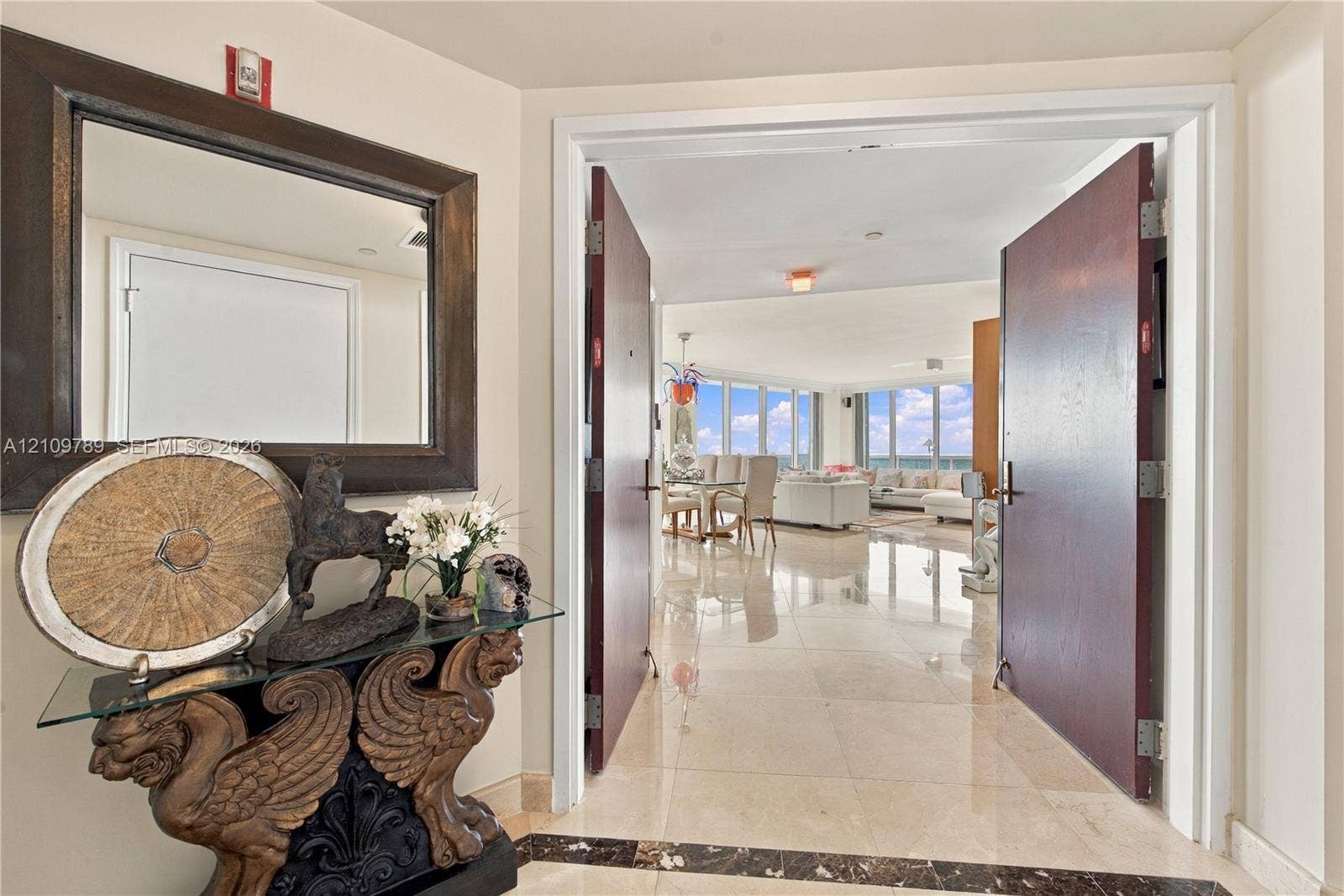 9595 Collins Avenue, #N6-B, Surfside, Surfside, FL 33154 Foyer entrance featuring dual solid-core doors, polished stone flooring with a decorative dark stone inlay, and floor-to-ceiling windows