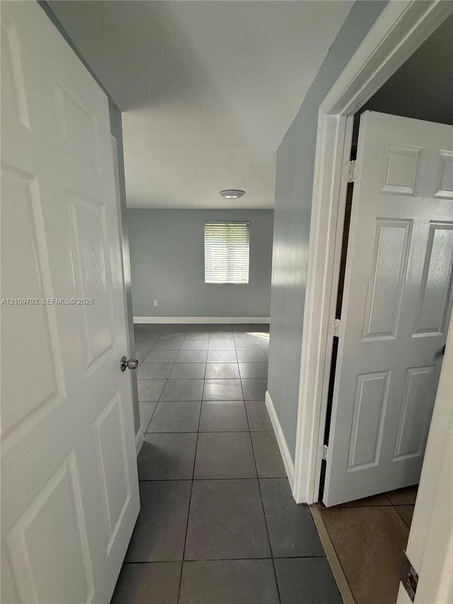 Six-panel interior doors, neutral-toned wall paint, and large-format ceramic tile flooring