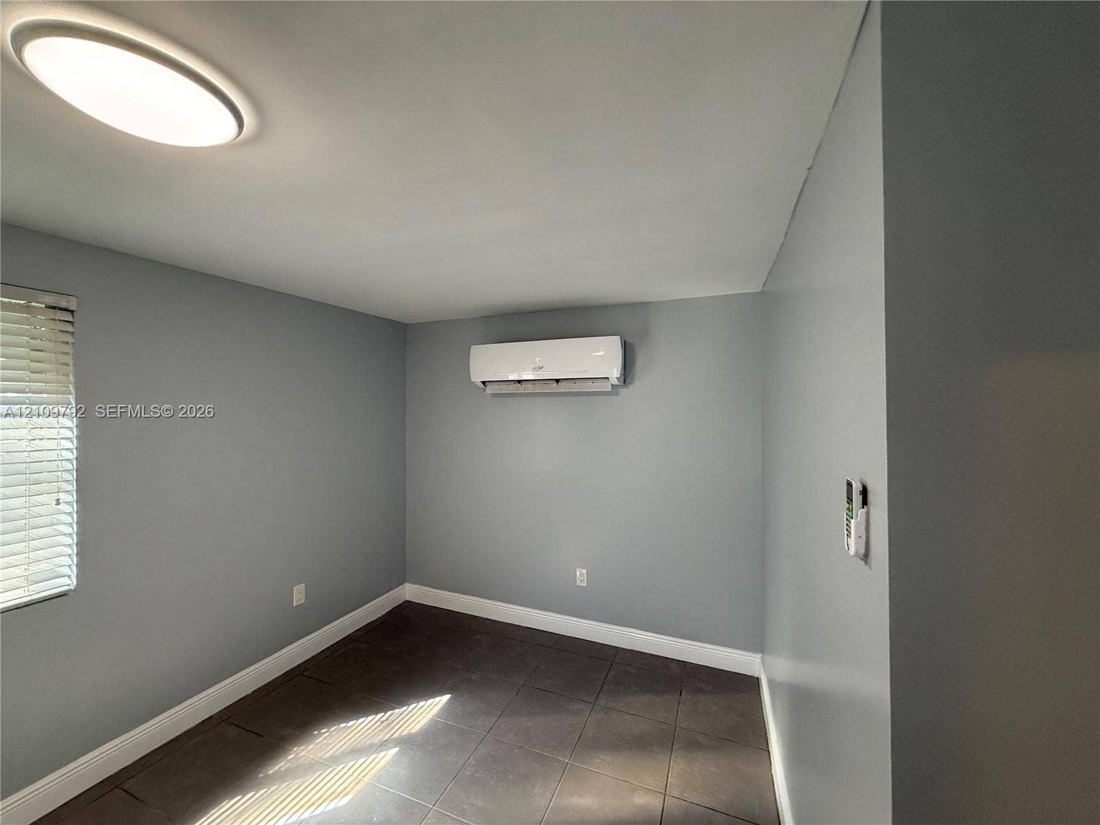 Wall-mounted ductless HVAC unit, large-format tile flooring, and flush-mount ceiling lighting