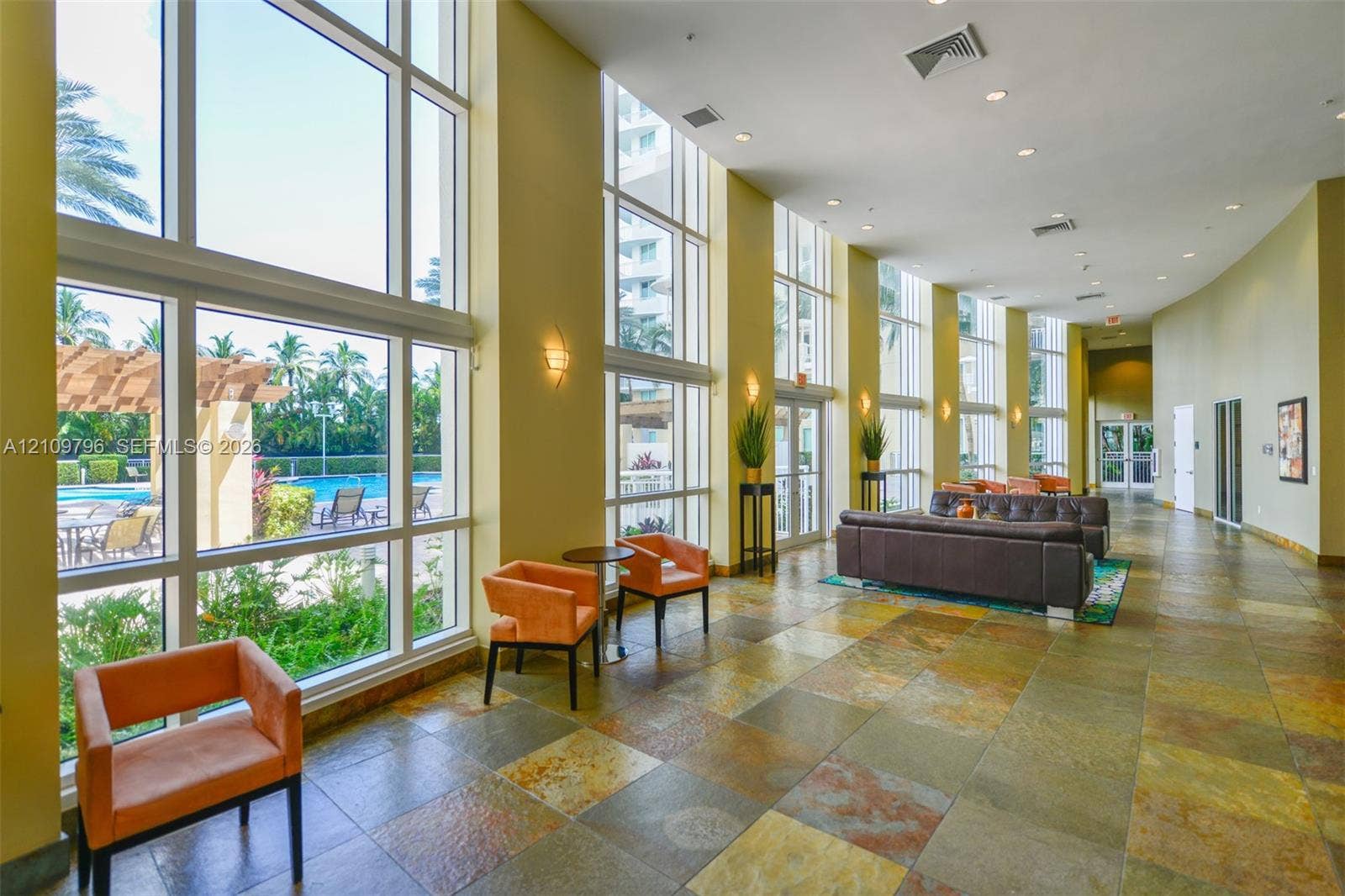 Floor-to-ceiling windows featuring expansive natural lighting, stone-tiled flooring, and recessed ceiling lighting