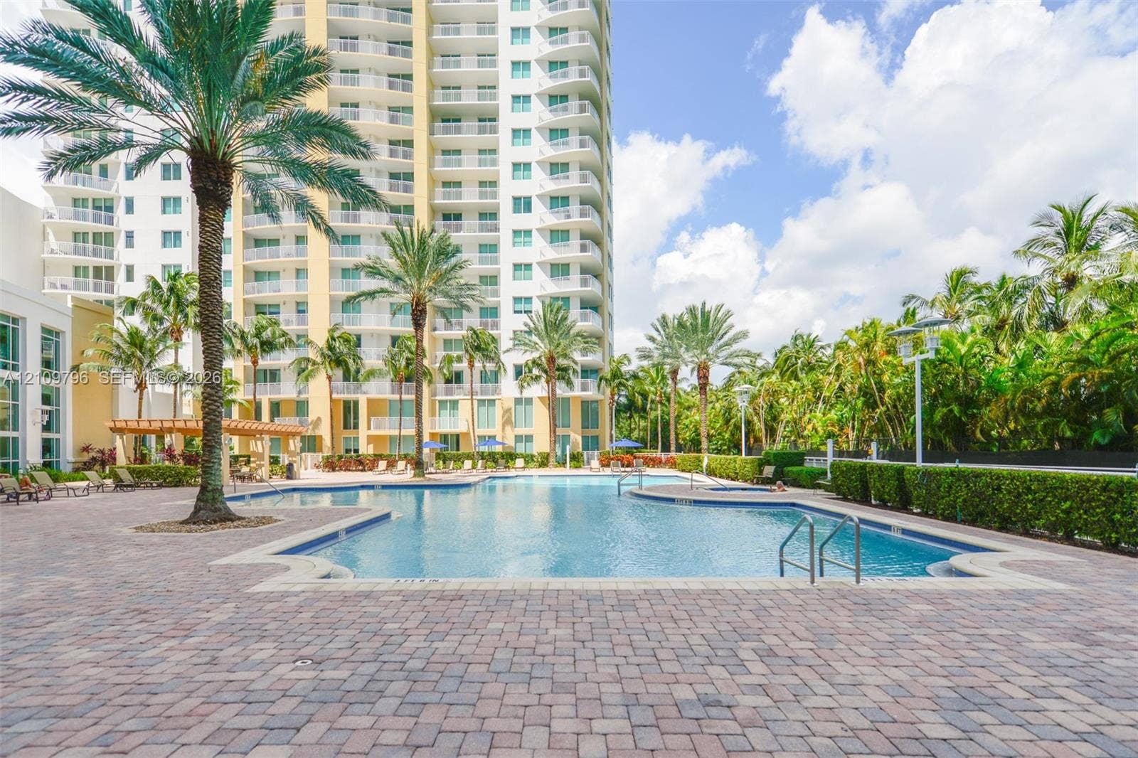 Swimming pool with perimeter paver decking, integrated spa, and mature palm landscaping