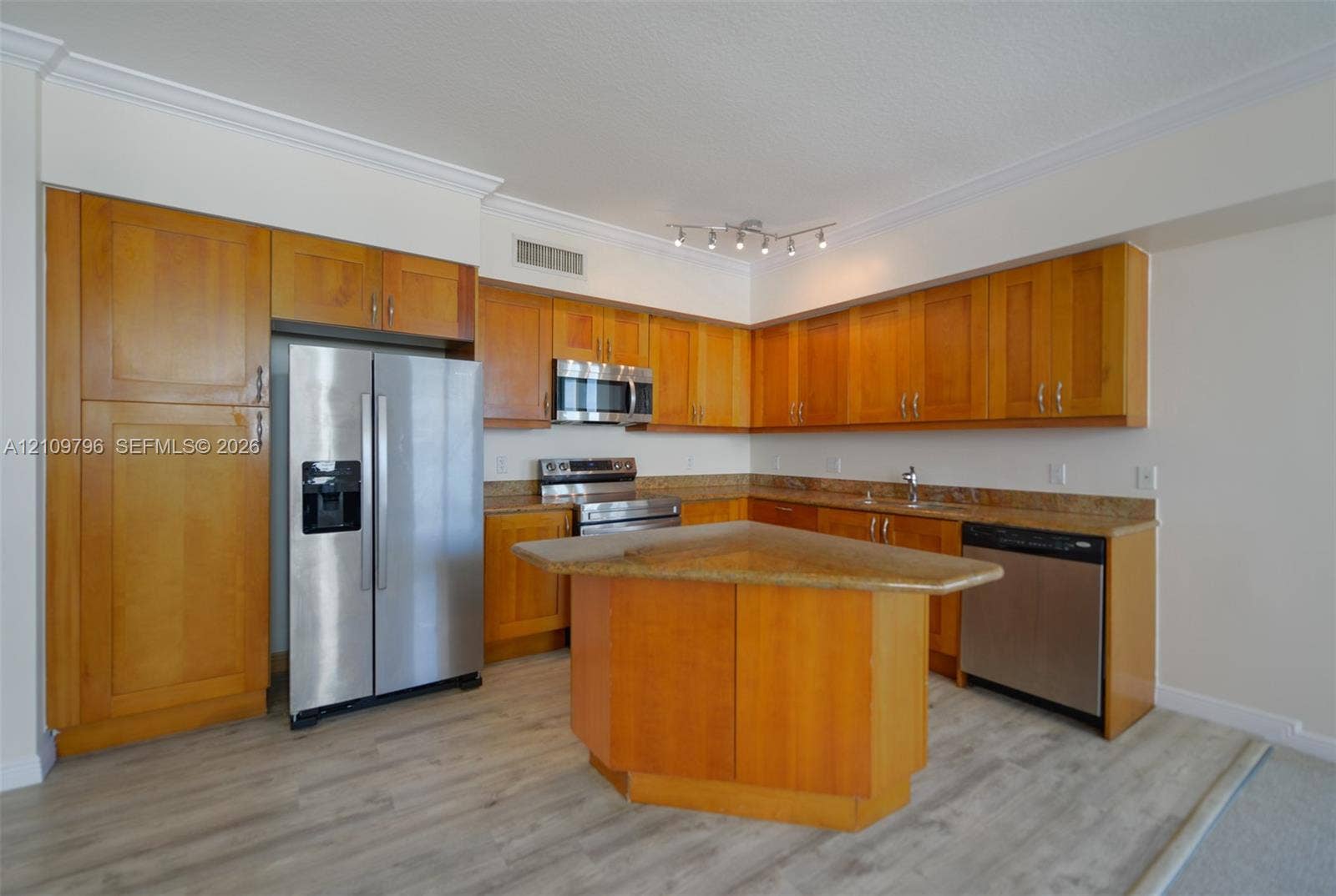 Kitchen featuring wood cabinetry, stone-surface countertops, central island, stainless steel appliances, and wood-finish flooring