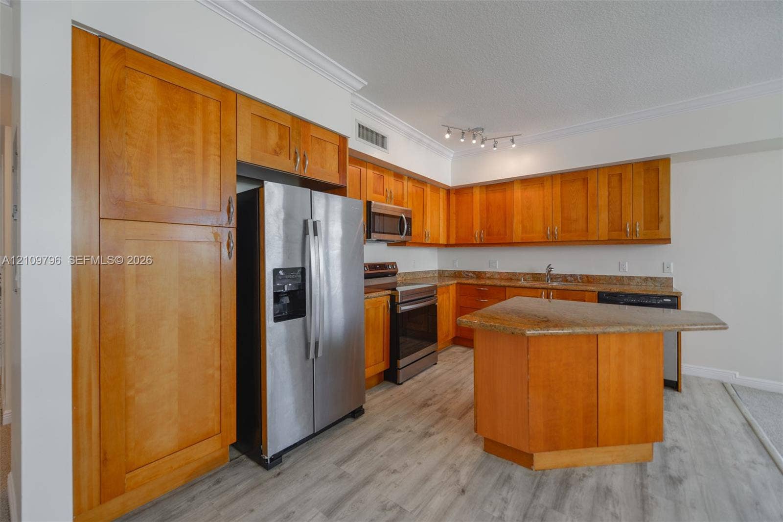 Kitchen featuring wood cabinetry, stone countertops, stainless steel appliances, a center island, and wood-finish flooring