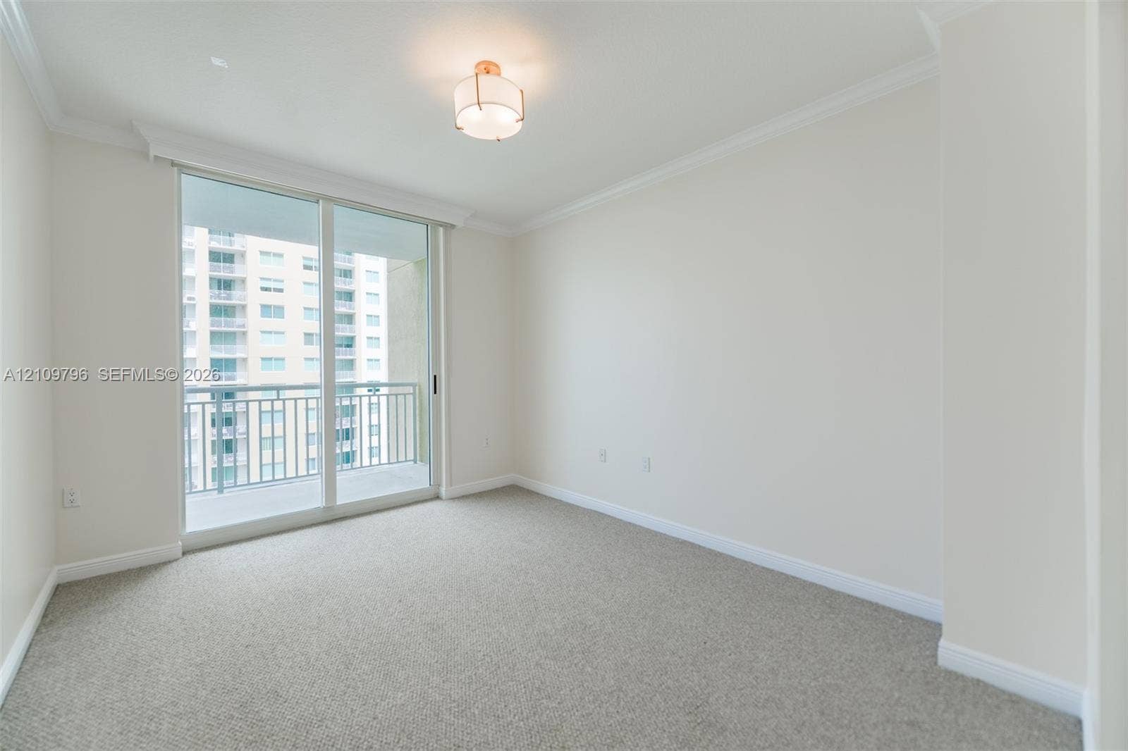 Neutral interior featuring carpeting, crown molding, a semi-flush mount light fixture, and a sliding glass door providing access to an exterior balcony