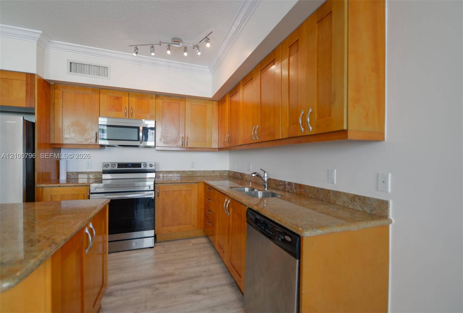 Kitchen featuring honey-toned wood cabinetry, stone countertops, stainless steel appliances, and wood-finish flooring