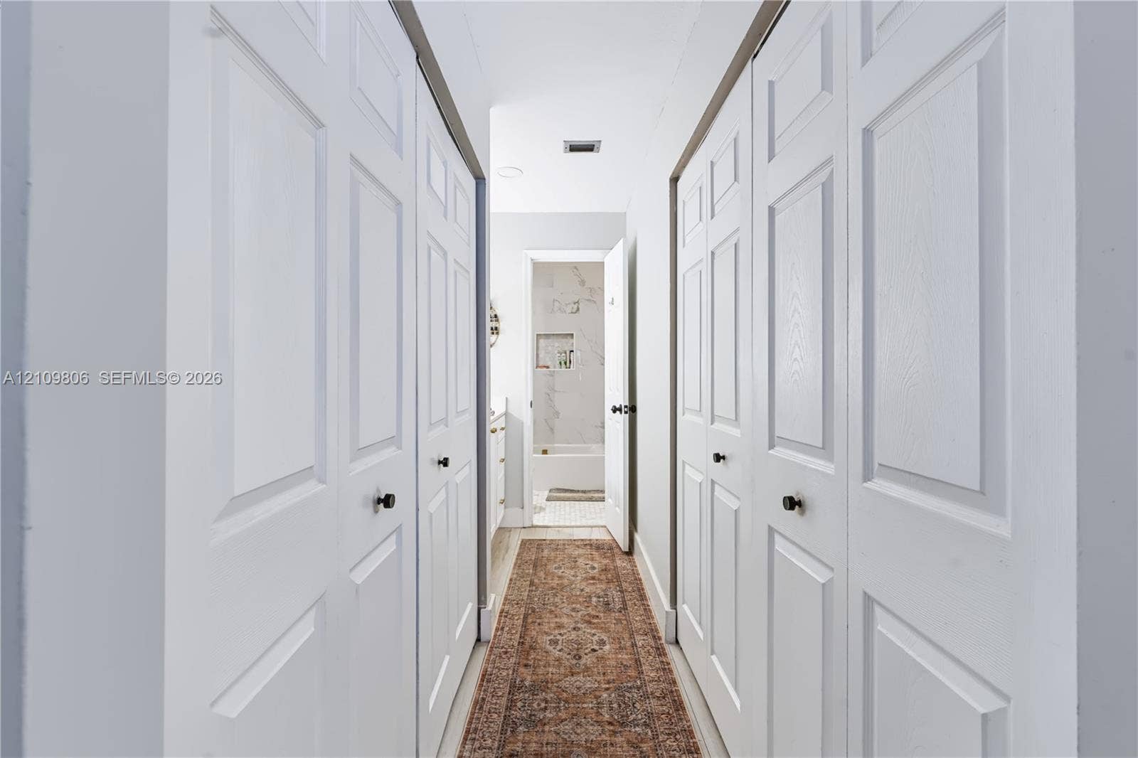 9123 SW 117th Court, Miami, FL 33186 Hallway featuring dual sets of white paneled bifold closet doors with matte black hardware