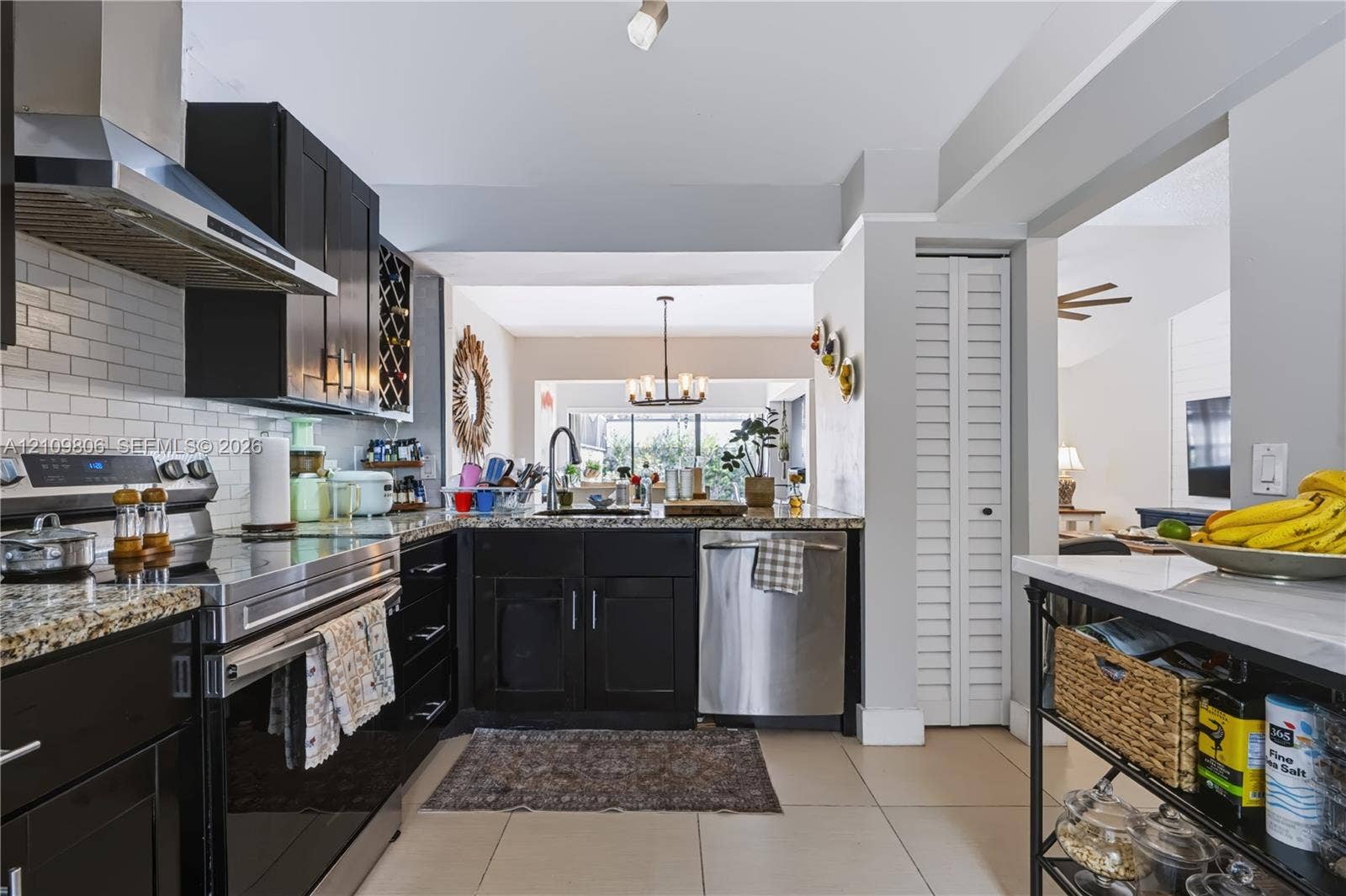 9123 SW 117th Court, Miami, FL 33186 Kitchen featuring dark cabinetry, stone countertops, a stainless steel range hood, a subway tile backsplash, and ceramic tile flooring