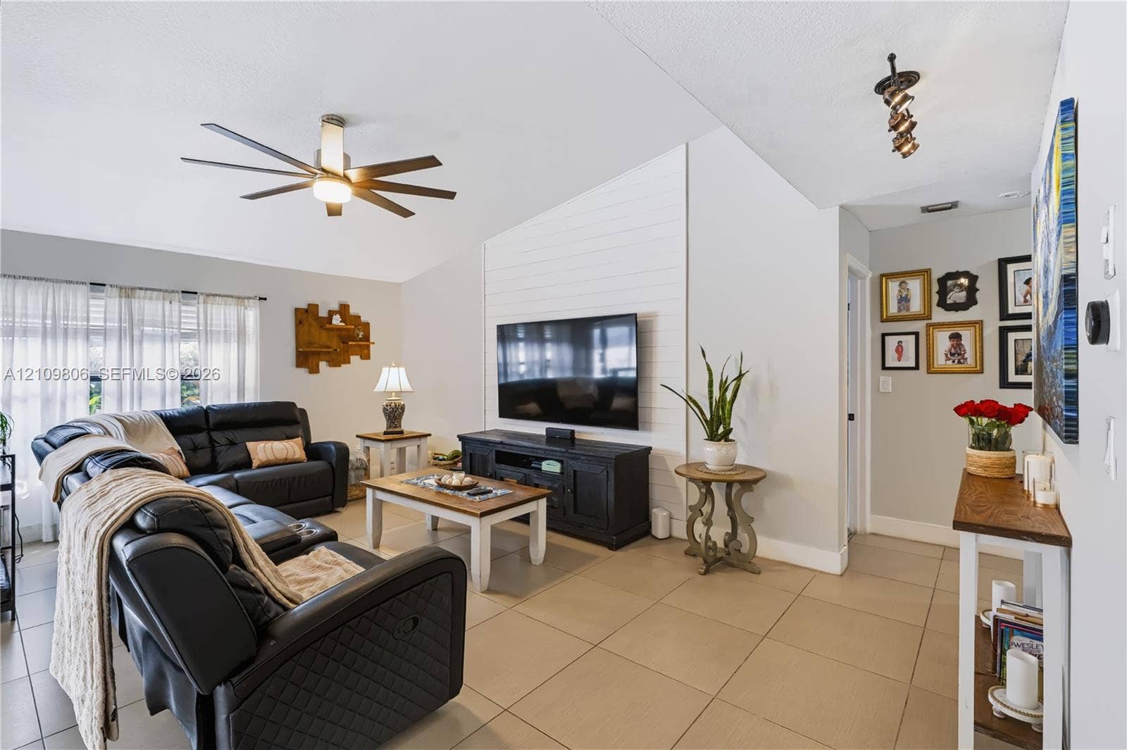 9123 SW 117th Court, Miami, FL 33186 Living area featuring a vaulted ceiling, large-format tile flooring, shiplap accent wall, and a multi-blade ceiling fan