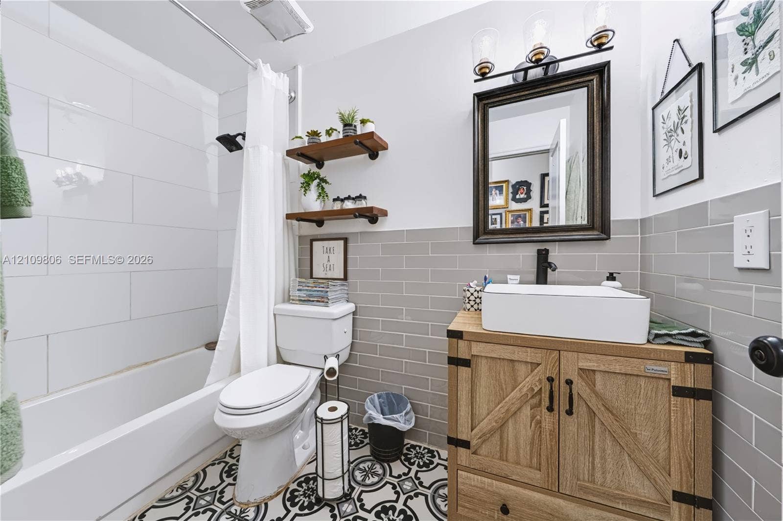 9123 SW 117th Court, Miami, FL 33186 Bathroom featuring wood-finish cabinetry, rectangular vessel sink, matte black hardware, grey subway tile wainscoting, and patterned floor tile