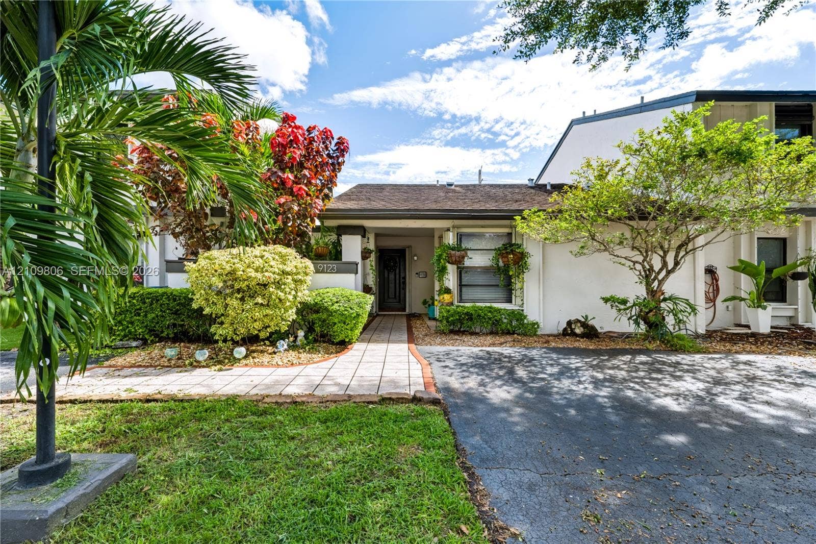 9123 SW 117th Court, Miami, FL 33186 Exterior facade featuring a paved walkway, shingled roofing, mature landscaping, and an asphalt driveway