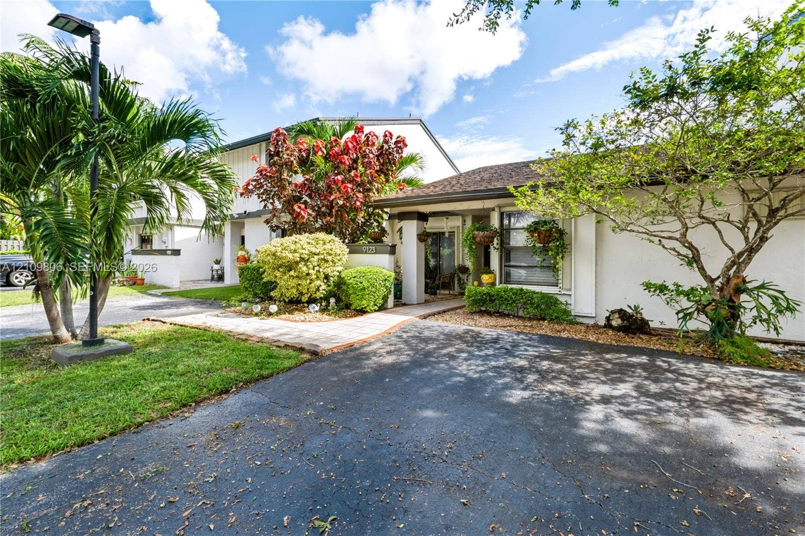9123 SW 117th Court, Miami, FL 33186 Exterior facade featuring a paved walkway, asphalt driveway, and mature landscaping